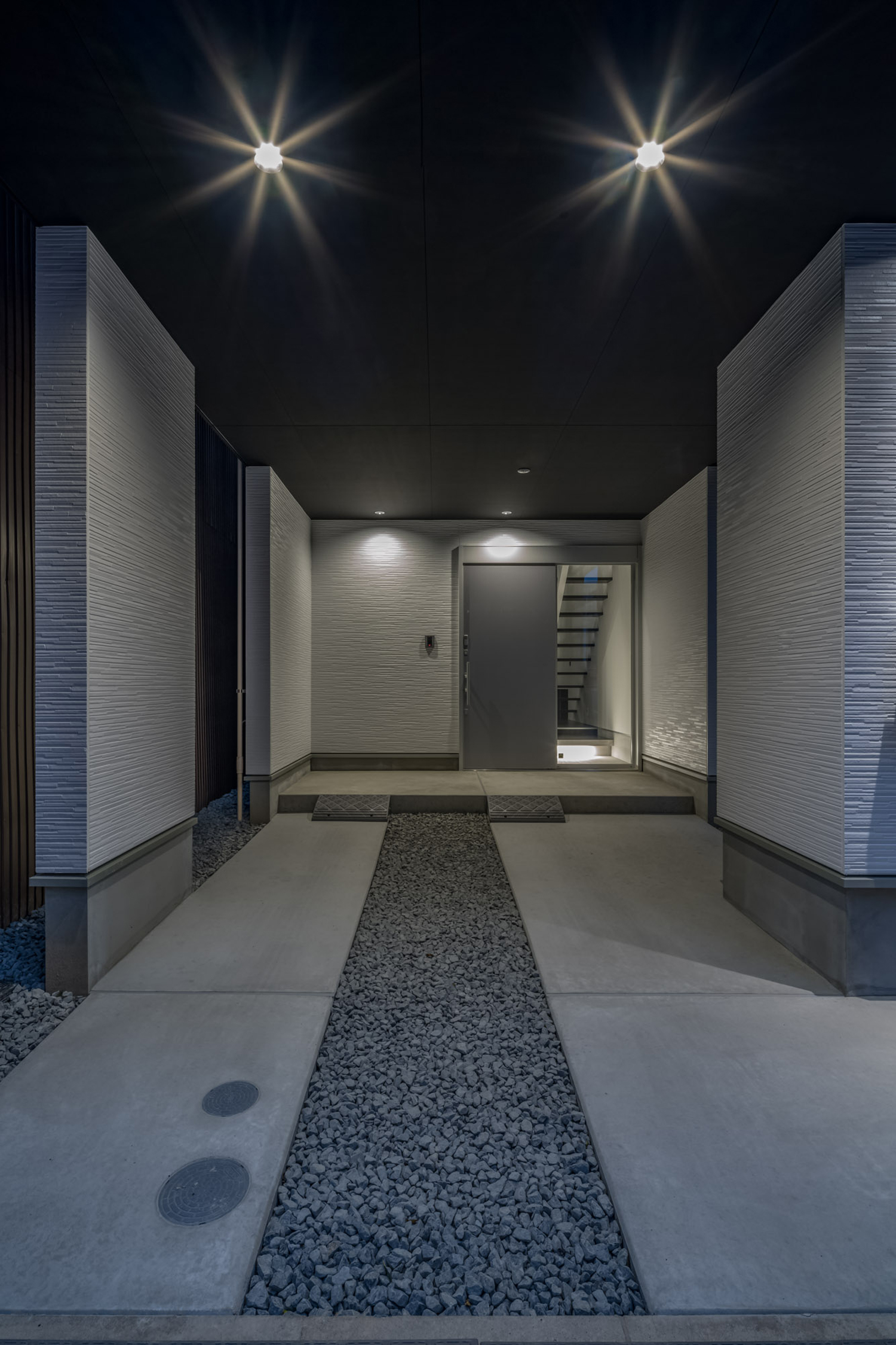 白い壁に囲まれ、黒い天井にはダウンライトが取り付けられたコンクリートの玄関ポーチ・デザイン住宅 注文住宅・デザイン住宅建築実例_『CASE646 鏡の家』_外観