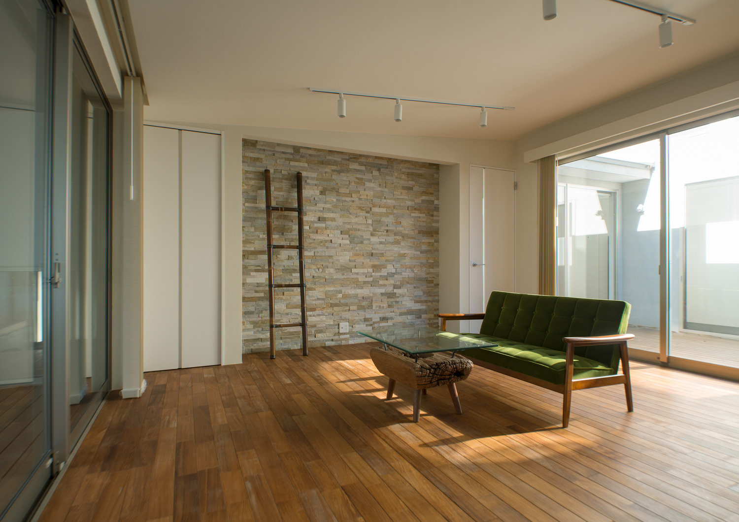 梯子や緑のソファー、ガラスのサイドテーブルなどが置かれた、大開口窓のあるフローリングのLDK・デザイン住宅 注文住宅・デザイン住宅建築実例_『CASE649 光の通り道』_LDK