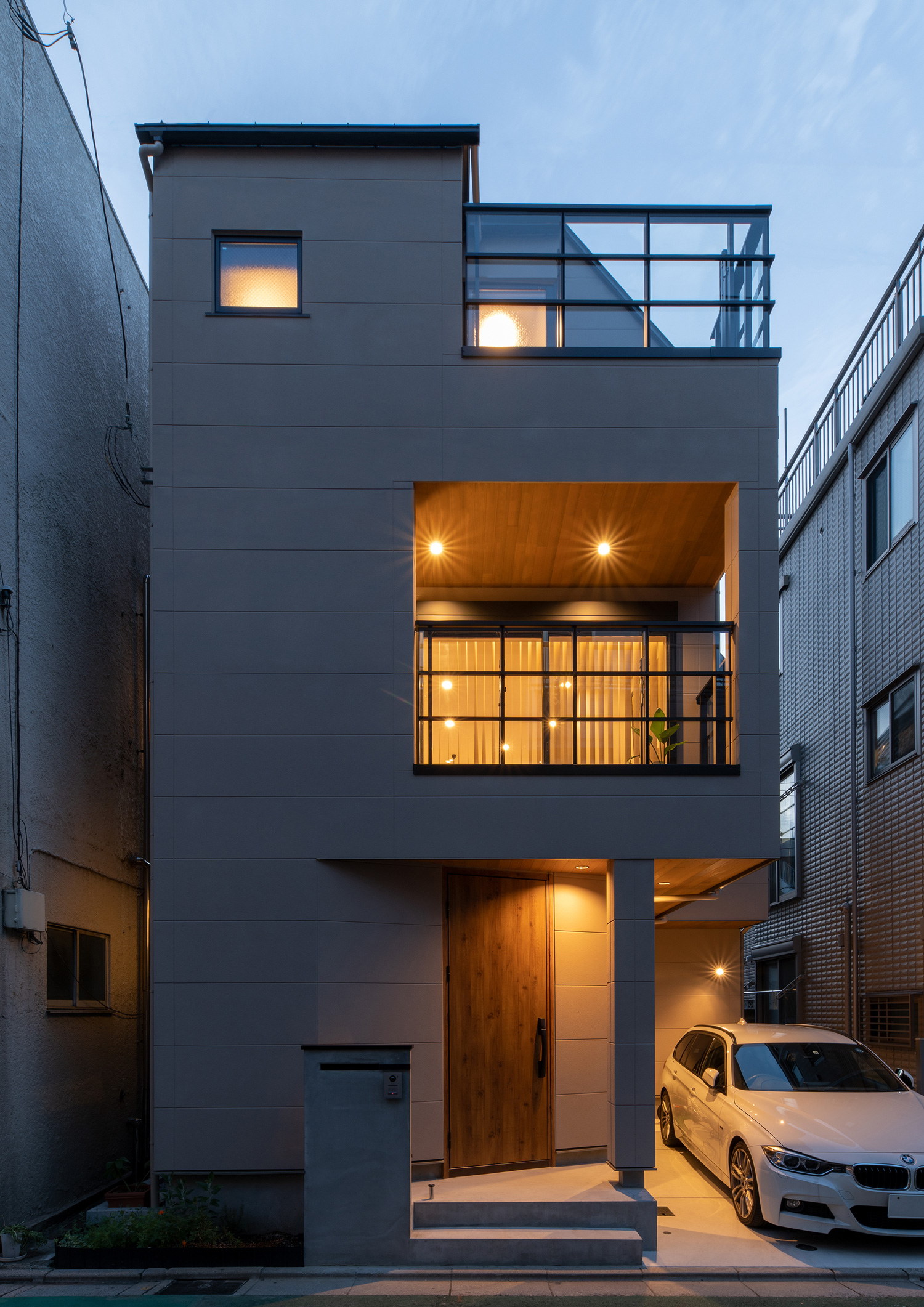 ベランダの軒天井に設けられたダウンライトや玄関扉の照明に照らされた外観・デザイン住宅 注文住宅・デザイン住宅建築実例_『CASE651 New_tral House』_外観