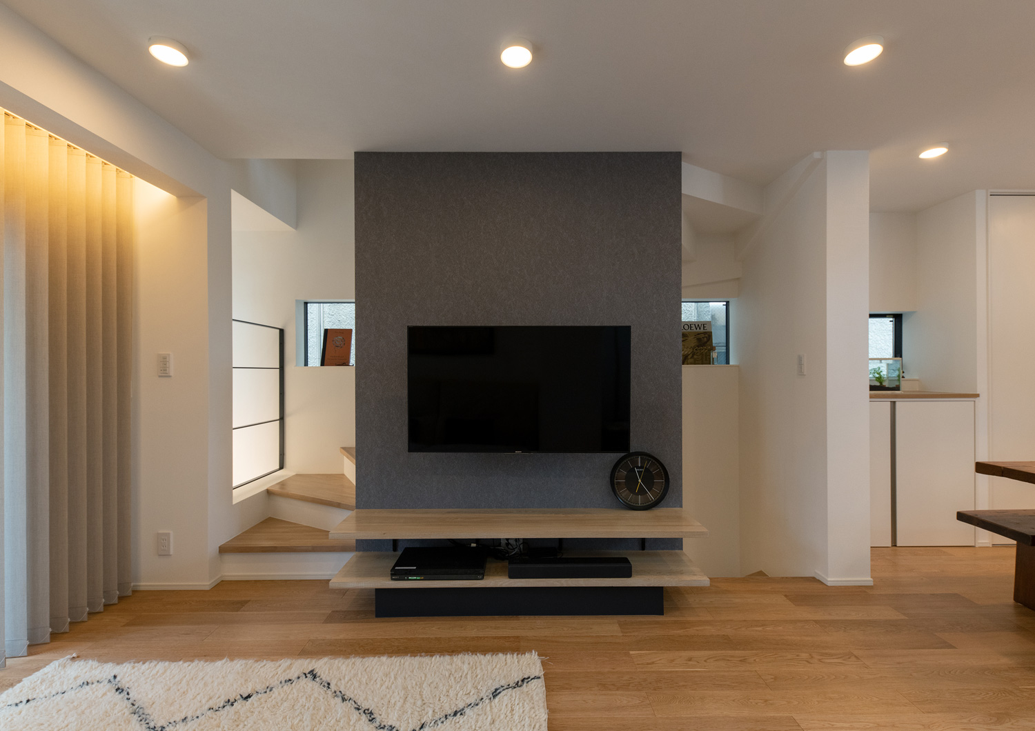 階段を隠すようなグレーのアクセントウォールにテレビが設けられたLDK・デザイン住宅 注文住宅・デザイン住宅建築実例_『CASE651 New_tral House』_LDK