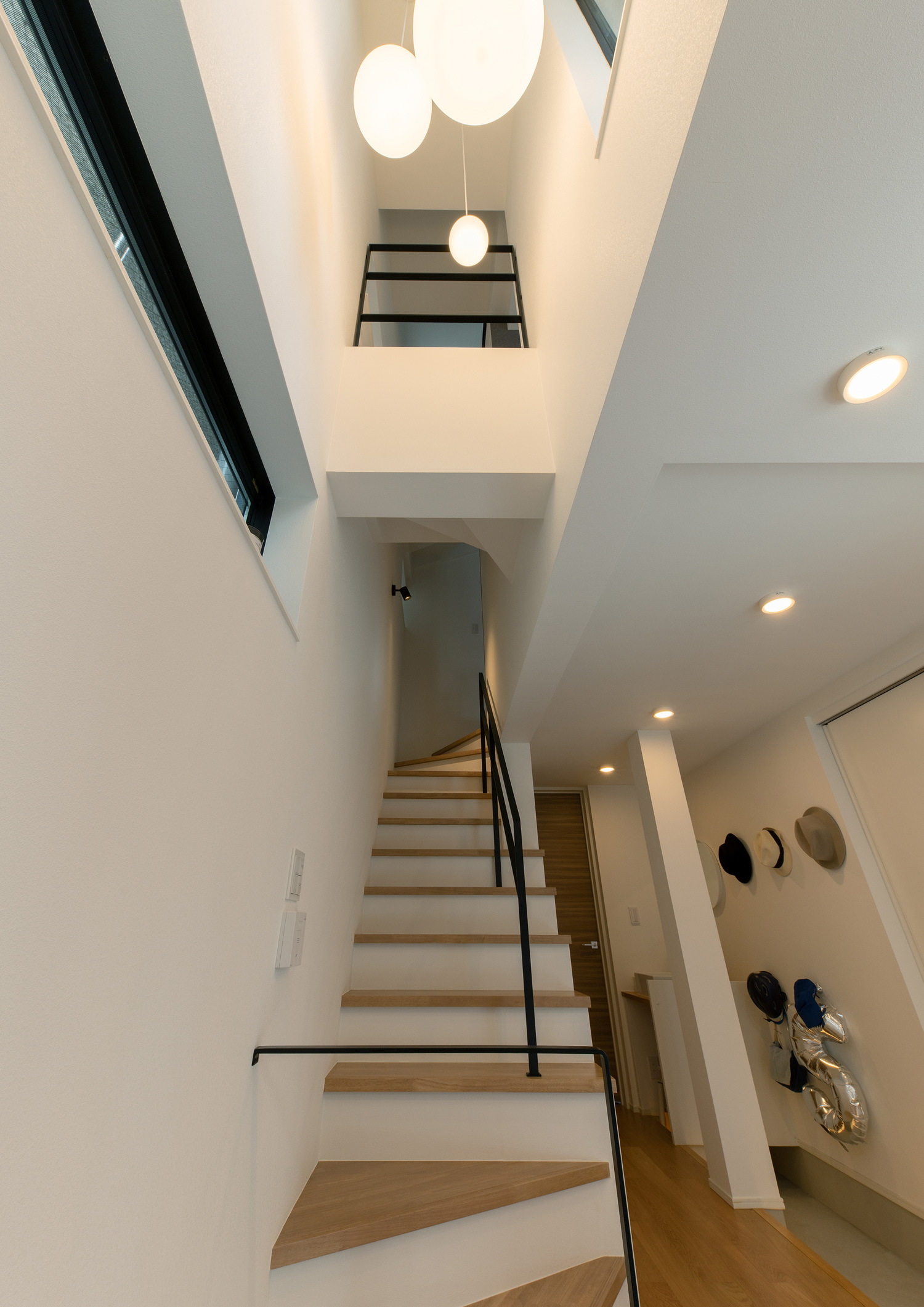 天井に丸いペンダントライトが設けられた階段部分の吹き抜け・デザイン住宅 注文住宅・デザイン住宅建築実例_『CASE651 New_tral House』_階段