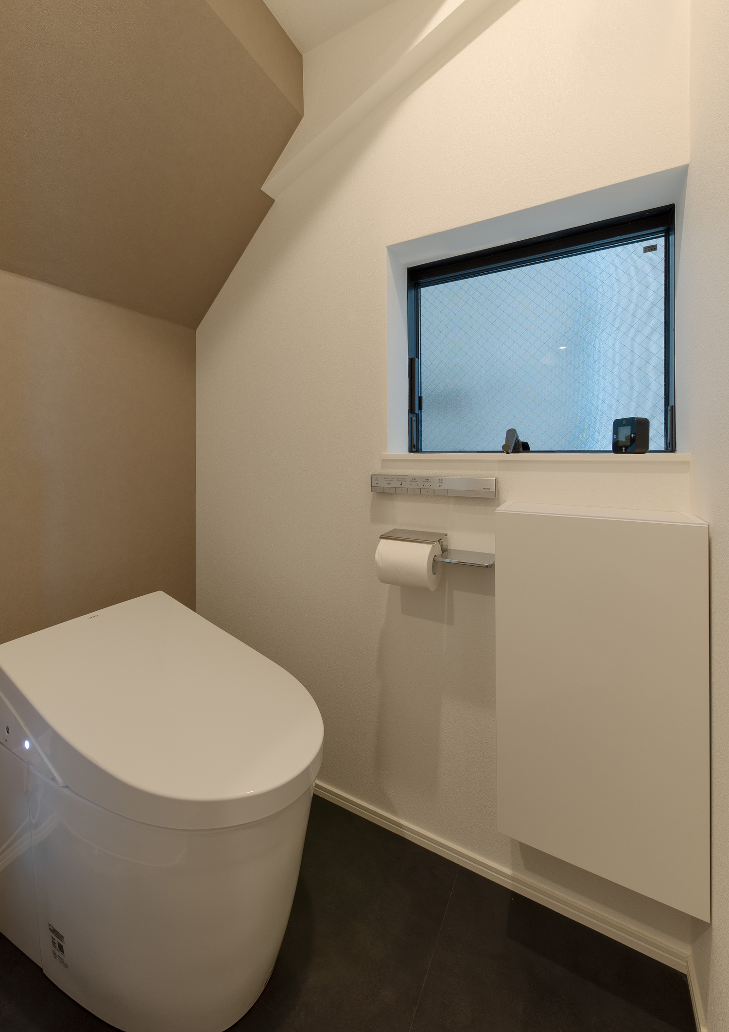 ベージュのアクセントクロスが設けられ、窓のある母屋下がりのトイレ・デザイン住宅 注文住宅・デザイン住宅建築実例_『CASE651 New_tral House』_トイレ