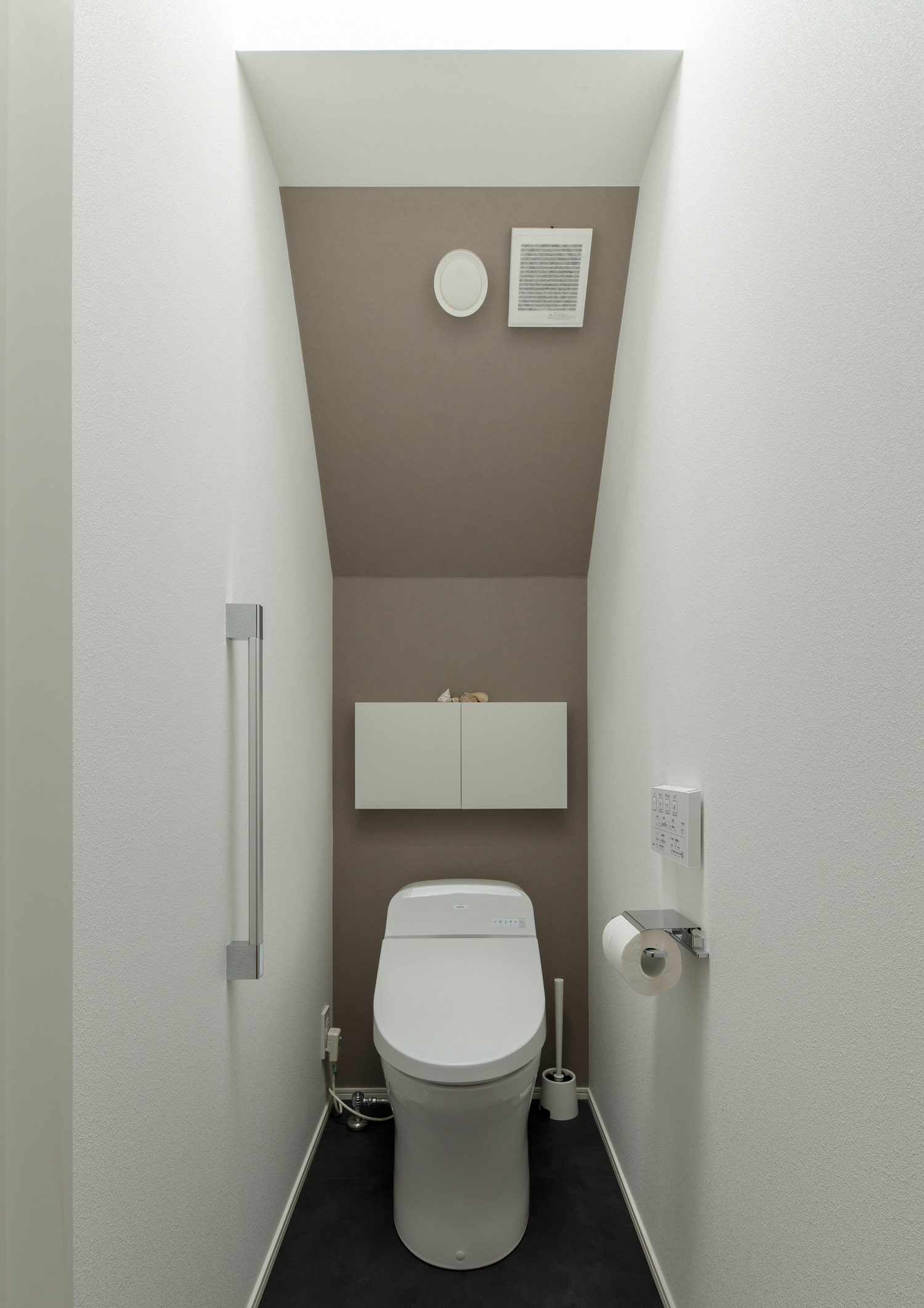 ベージュのアクセントクロスに収納が取り付けられた母屋下がりのトイレ・デザイン住宅 注文住宅・デザイン住宅建築実例_『CASE651 New_tral House』_トイレ
