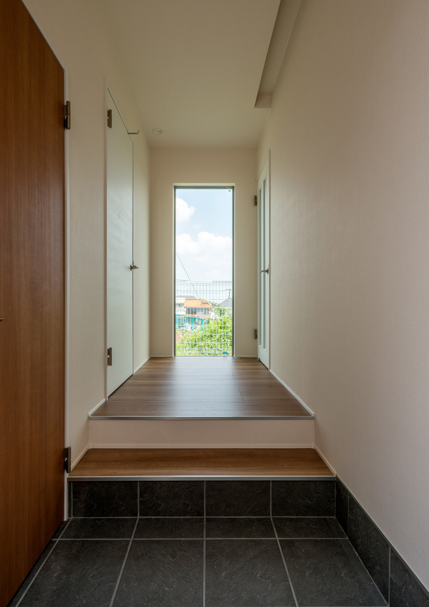 黒いタイルの玄関の正面に外の景色が見える窓がある様子・デザイン住宅 注文住宅・デザイン住宅建築実例_『CASE650 景色を持つ家』_玄関