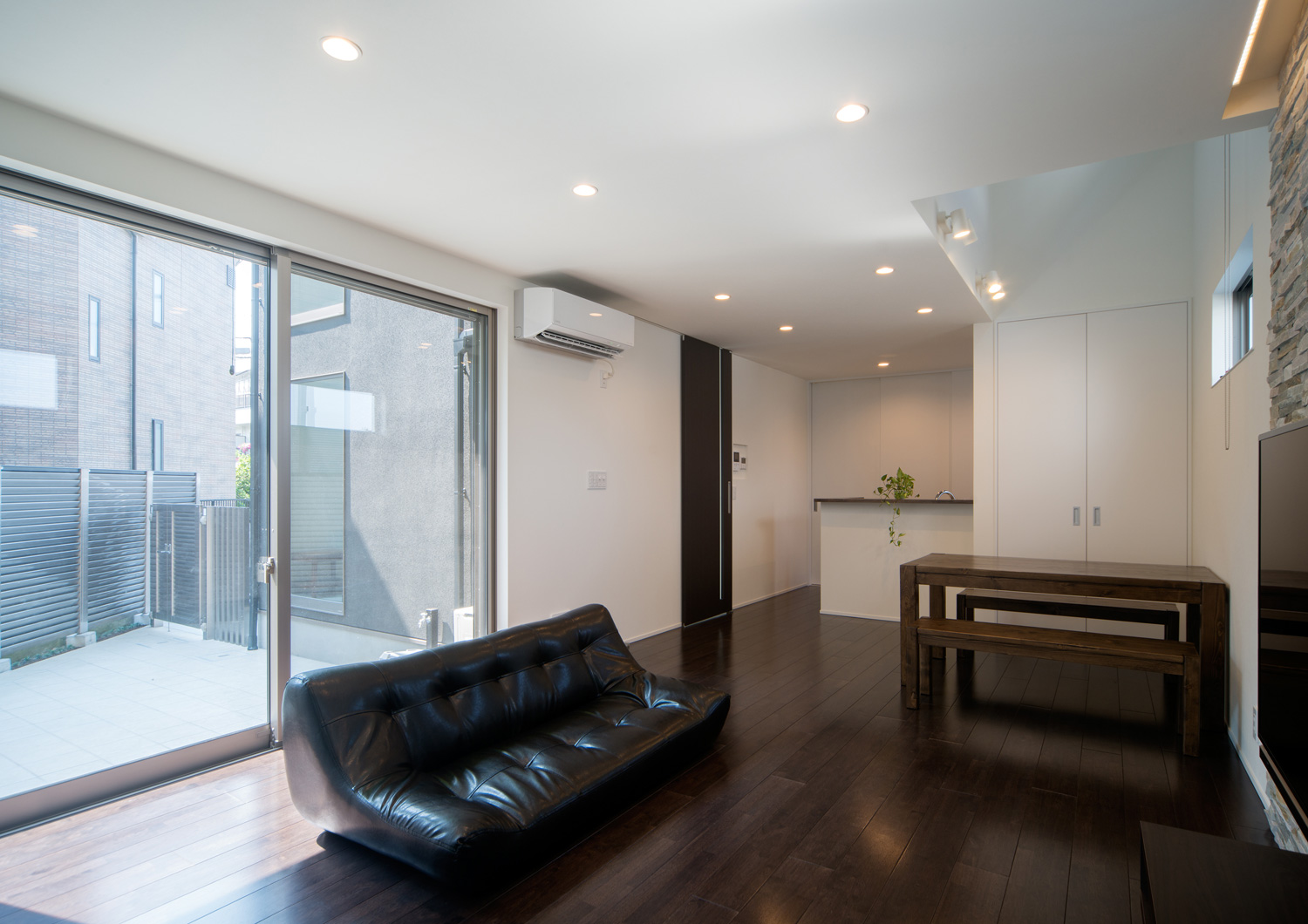 黒いソファーを置いた濃い色のフローリングのLDK・デザイン住宅 注文住宅・デザイン住宅建築実例_『CASE652 2つの吹抜けを持つ家。』_LDK