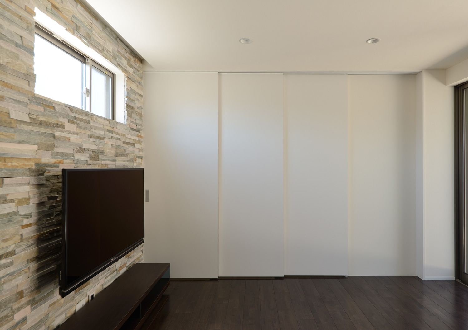 窓やテレビが設けられた石のアクセントウォール・デザイン住宅 注文住宅・デザイン住宅建築実例_『CASE652 2つの吹抜けを持つ家。』_LDK