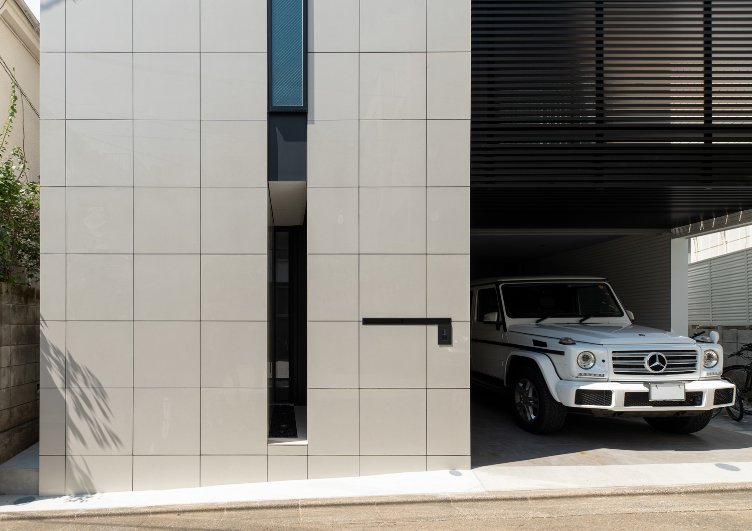 白いタイルの外壁に、縦長のスリット窓が設けられたインナーガレージのある住宅・デザイン住宅 注文住宅・デザイン住宅建築実例_『CASE653 せんのいえ』_外観