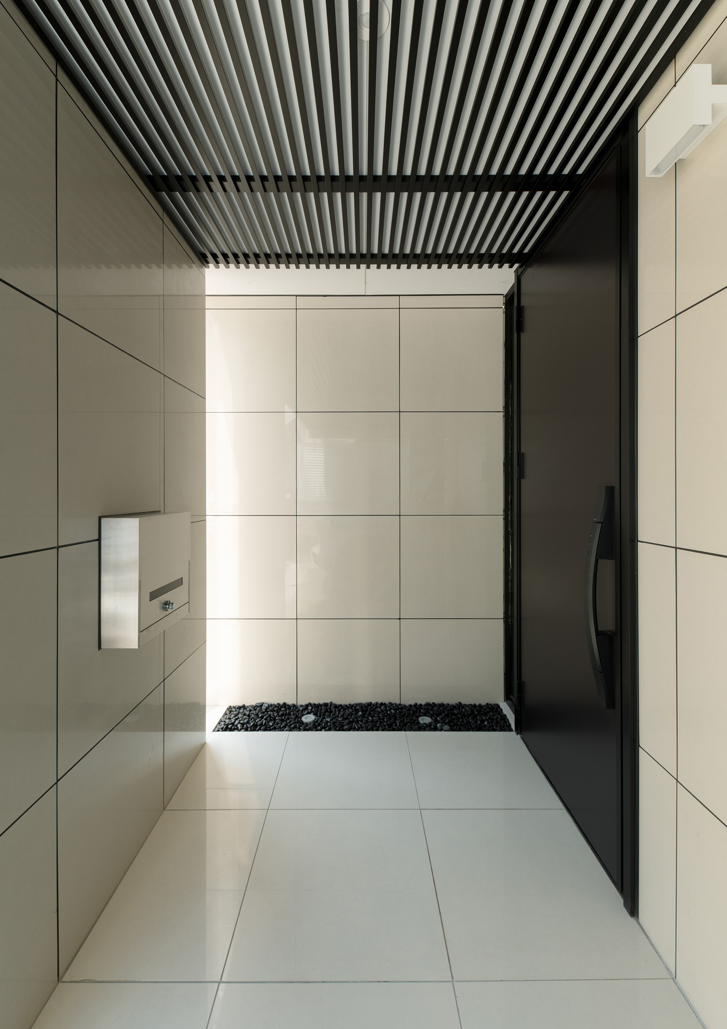 床や壁が白いタイルで、天井がルーバーになった玄関ポーチ・デザイン住宅 注文住宅・デザイン住宅建築実例_『CASE653 せんのいえ』_外観