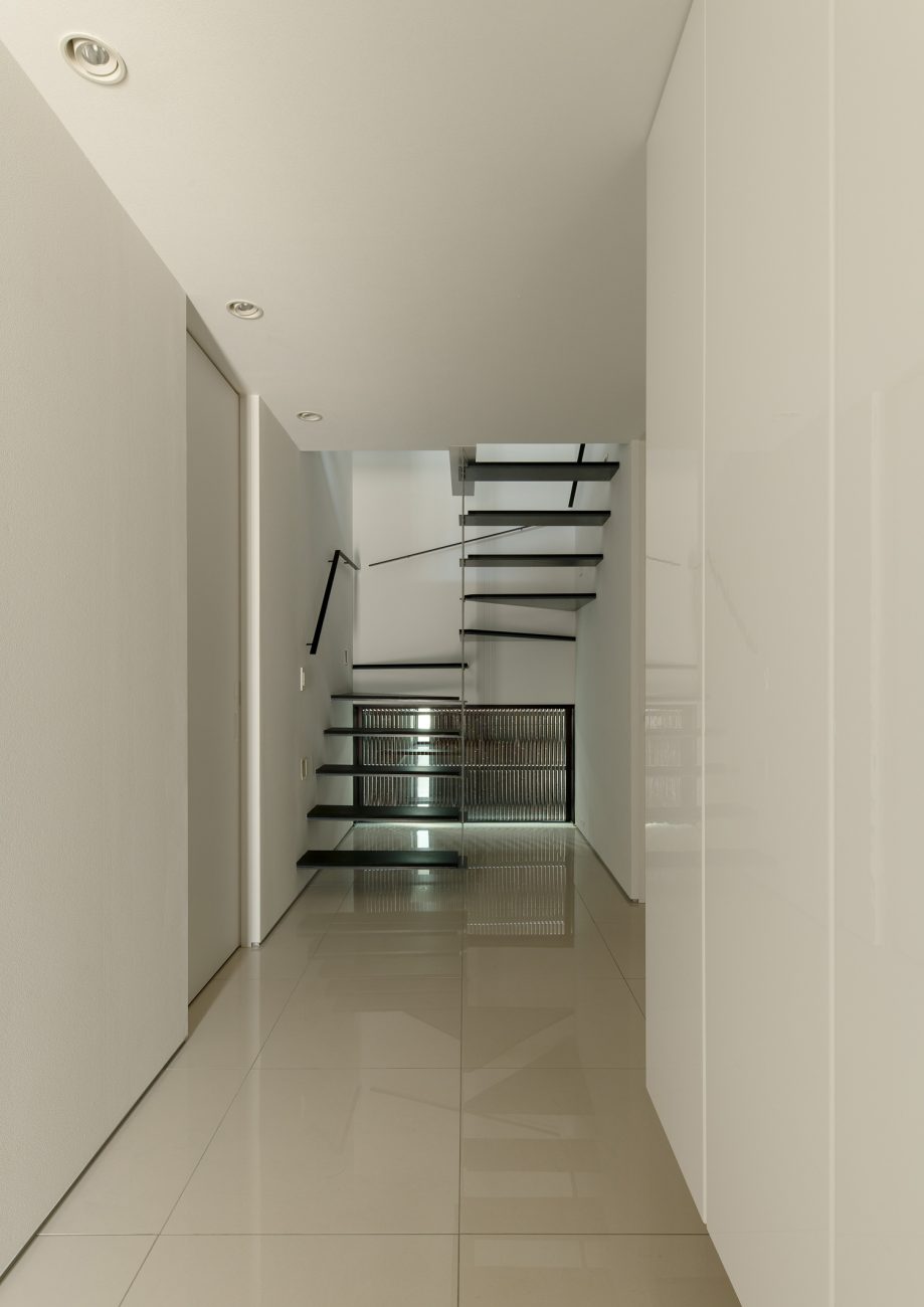 白いタイルの玄関の先に黒いスケルトン階段が見える様子・デザイン住宅 注文住宅・デザイン住宅建築実例_『CASE653 せんのいえ』_玄関