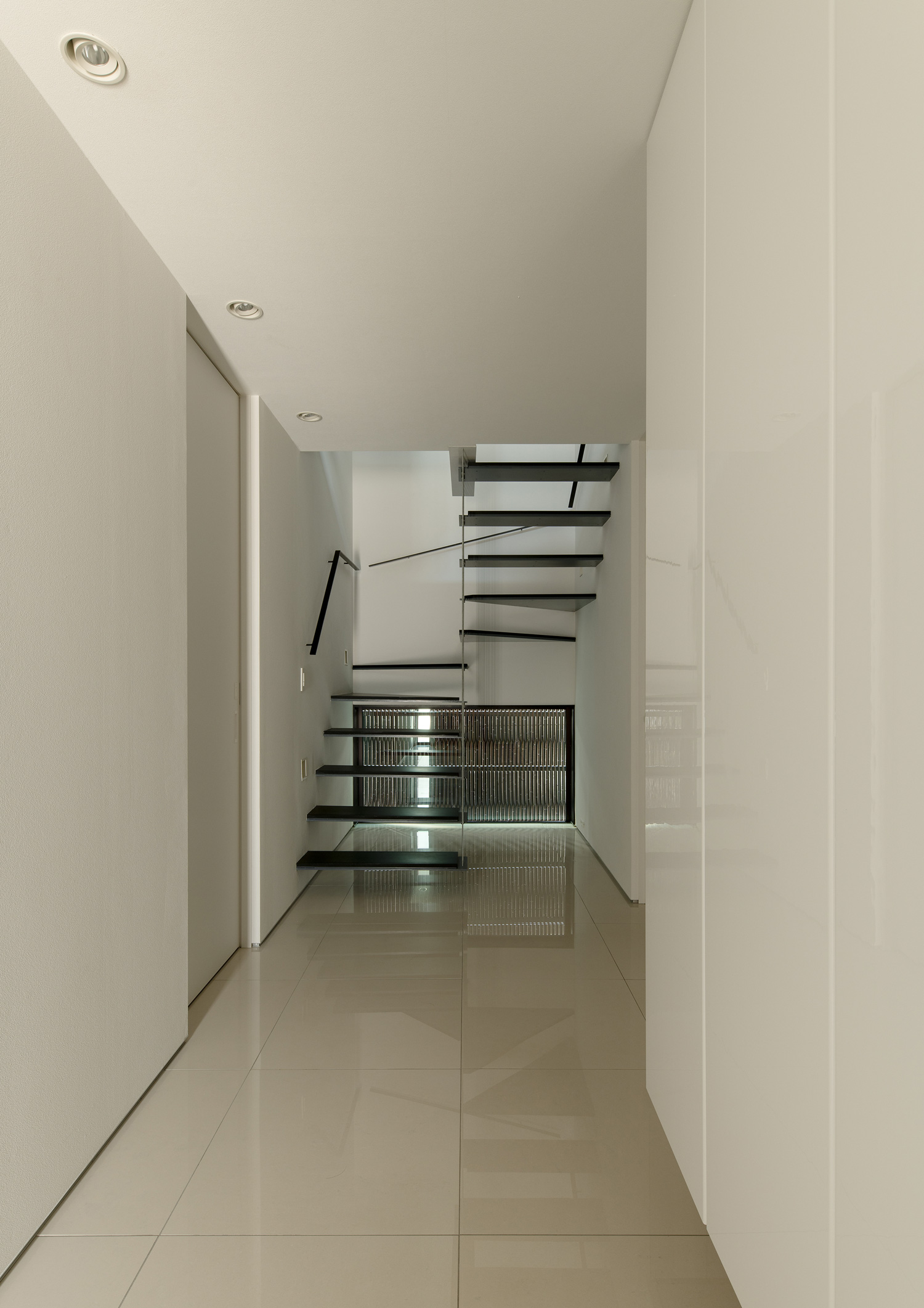 白いタイルの玄関の先に黒いスケルトン階段が見える様子・デザイン住宅 注文住宅・デザイン住宅建築実例_『CASE653 せんのいえ』_玄関