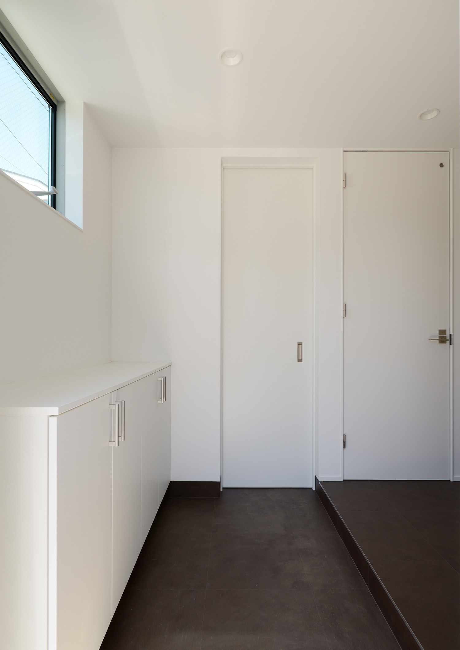 床が黒く、壁や建具が白で統一された玄関・デザイン住宅 注文住宅・デザイン住宅建築実例_『CASE654 circulating』_玄関