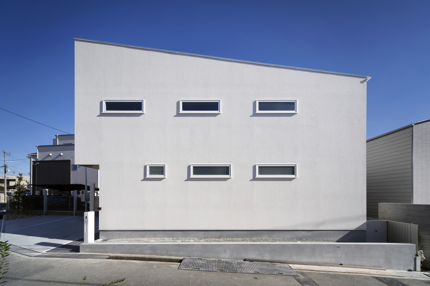 道路の傾斜と平行になるように合わせて屋根の傾斜が付けられ、小さな窓が均一に並んでいる住宅の外観・デザイン住宅 注文住宅・デザイン住宅建築実例_『CASE656 L x』_外観