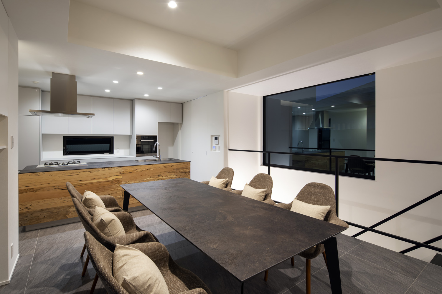 木材を使ったアイランドキッチンや六人掛けのダイニングテーブルがダウンライトによって照らされる様子・デザイン住宅 注文住宅・デザイン住宅建築実例_『CASE657 La scene』_LDK