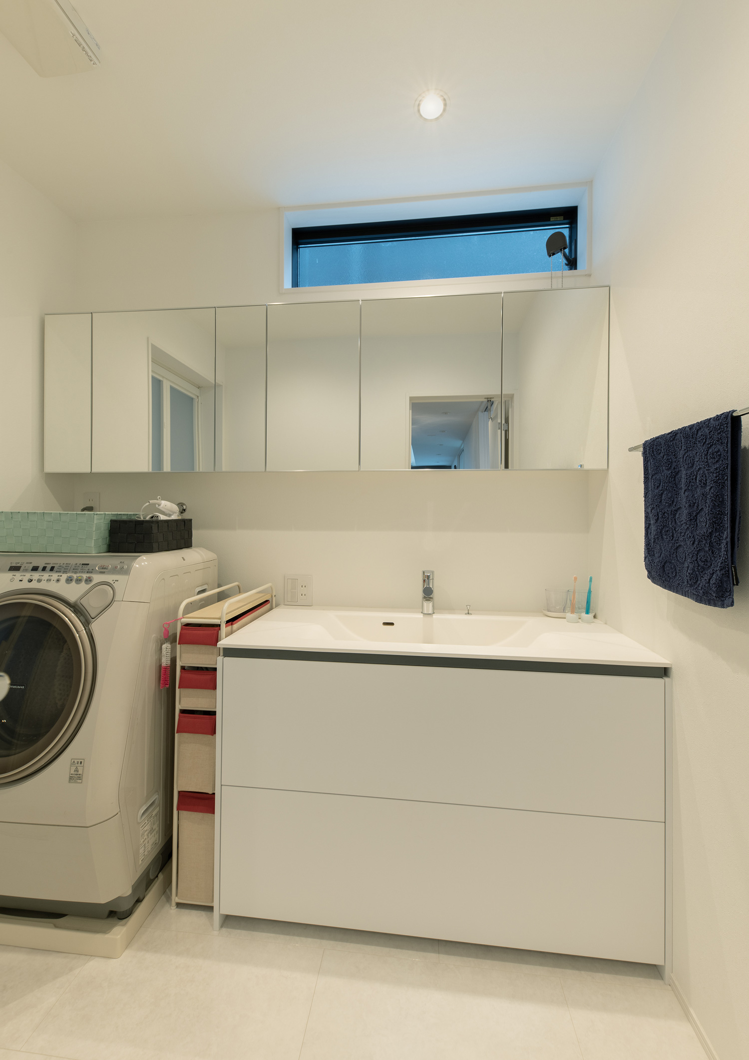 洗面台の横に洗濯機を置いた、スリット窓のある洗面所・デザイン住宅 注文住宅・デザイン住宅建築実例_『CASE658 connecting terminal』_浴室・洗面所