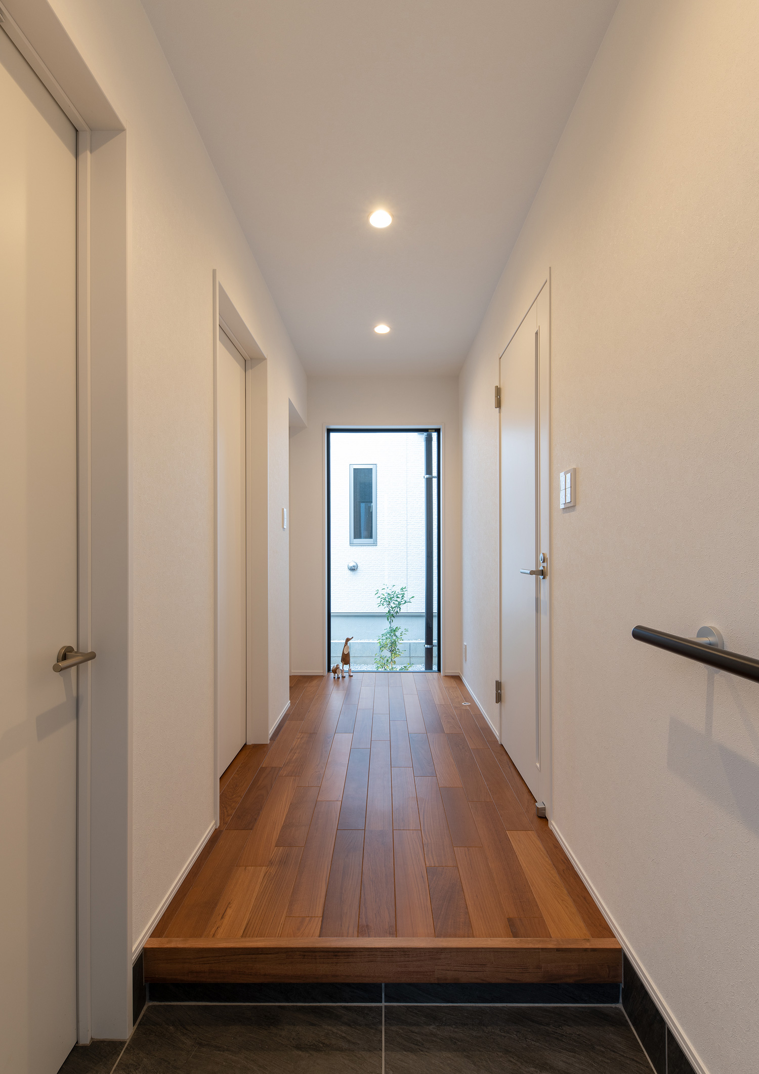 突き当りに植栽が見える窓があるフローリングの廊下・デザイン住宅 注文住宅・デザイン住宅建築実例_『CASE658 connecting terminal』_玄関