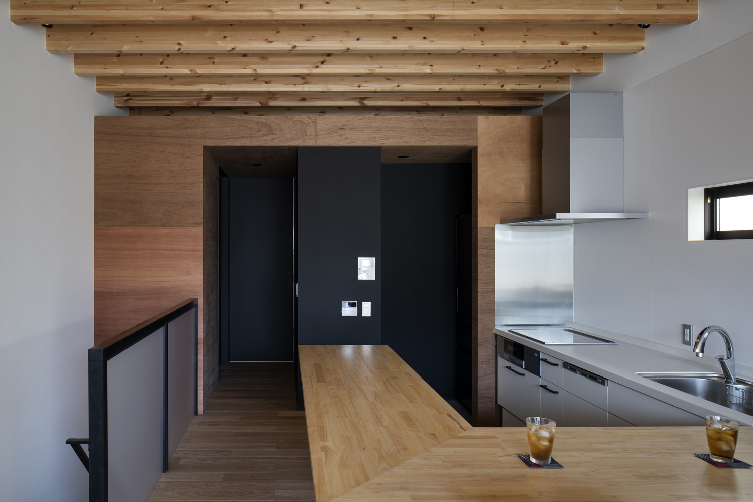 木目のインテリアを中心としたLDKの奥の壁が、黒くなっている様子・デザイン住宅 注文住宅・デザイン住宅建築実例_『CASE659 un cube』_キッチン