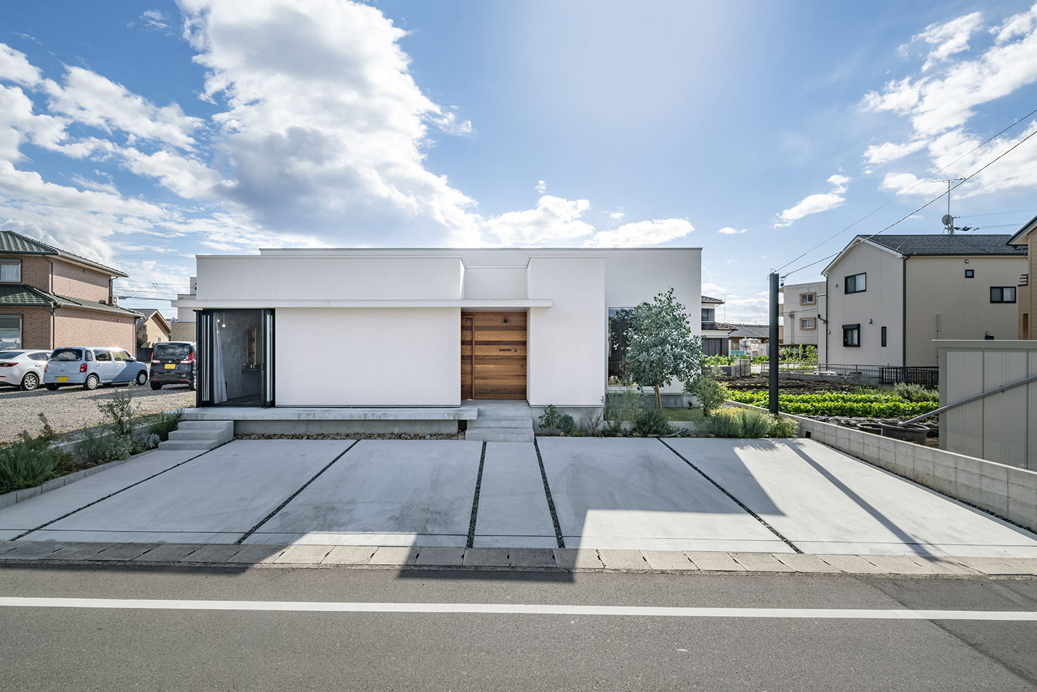 白一色の外壁に木製の玄関ドアが印象的な平屋