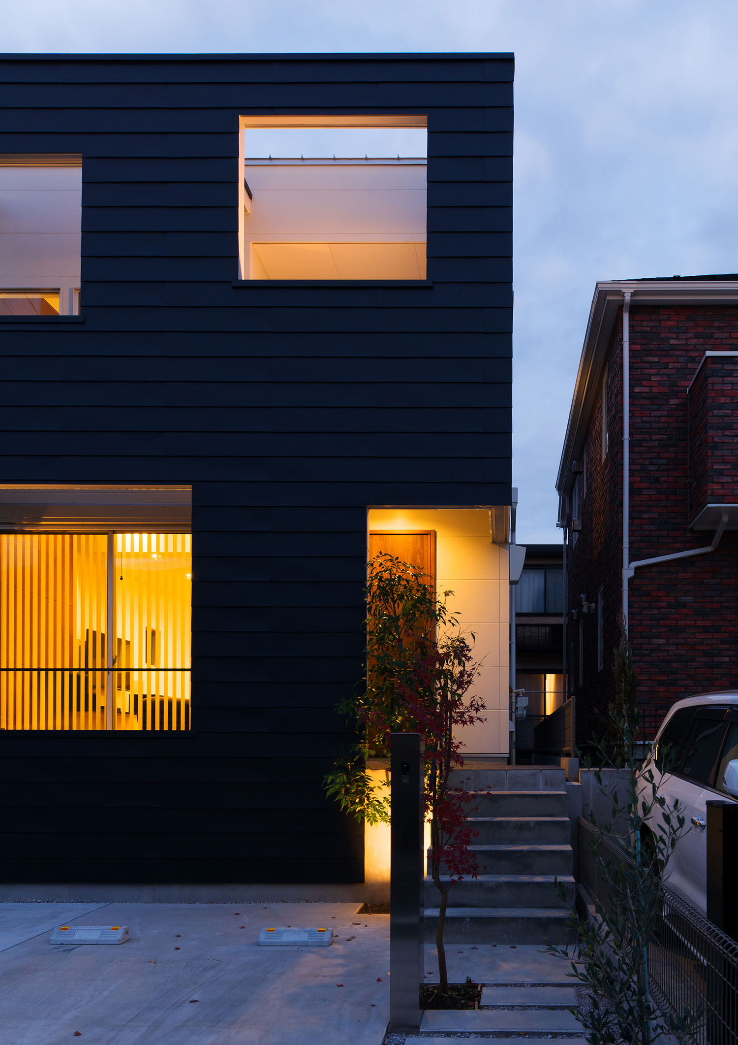 階段の玄関アプローチが照らされるガルバリウム鋼板の外壁の住宅・デザイン住宅 注文住宅・デザイン住宅建築実例_『CASE662 まくのいえ』_外観