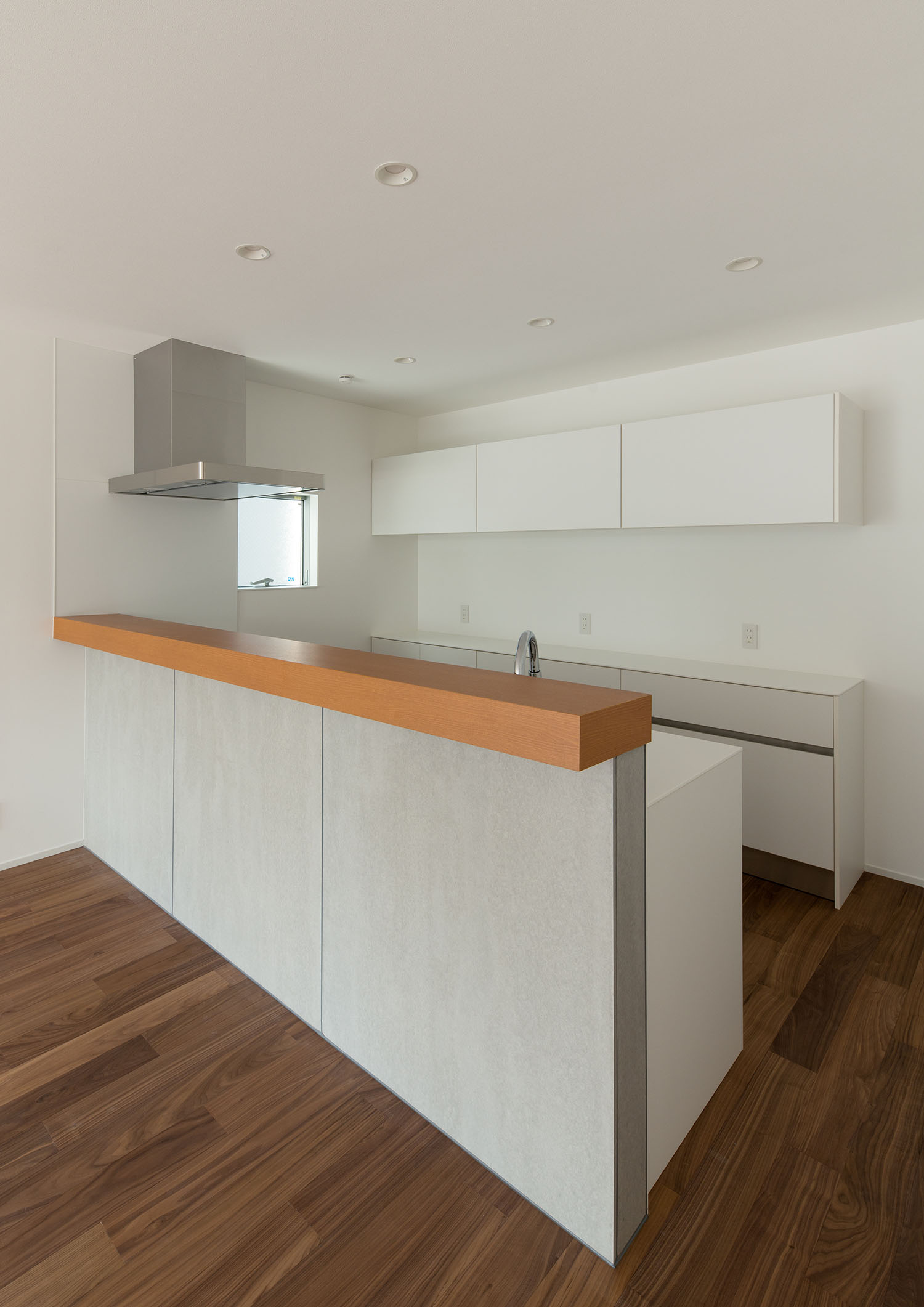 キッチン背面のカップボードが壁と同じ白色でまとめられた様子・デザイン住宅 注文住宅・デザイン住宅建築実例_『CASE662 まくのいえ』_キッチン