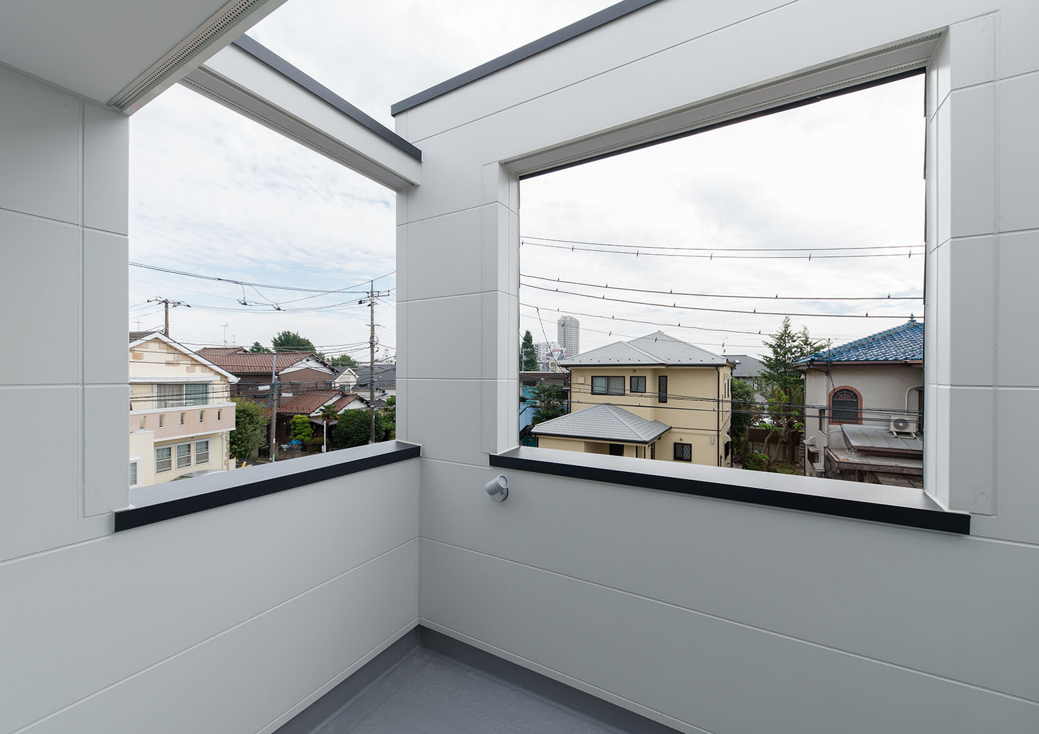 白い壁に囲まれたバルコニーの開口部から周囲の景色が見える様子・デザイン住宅 注文住宅・デザイン住宅建築実例_『CASE662 まくのいえ』_テラス・バルコニー