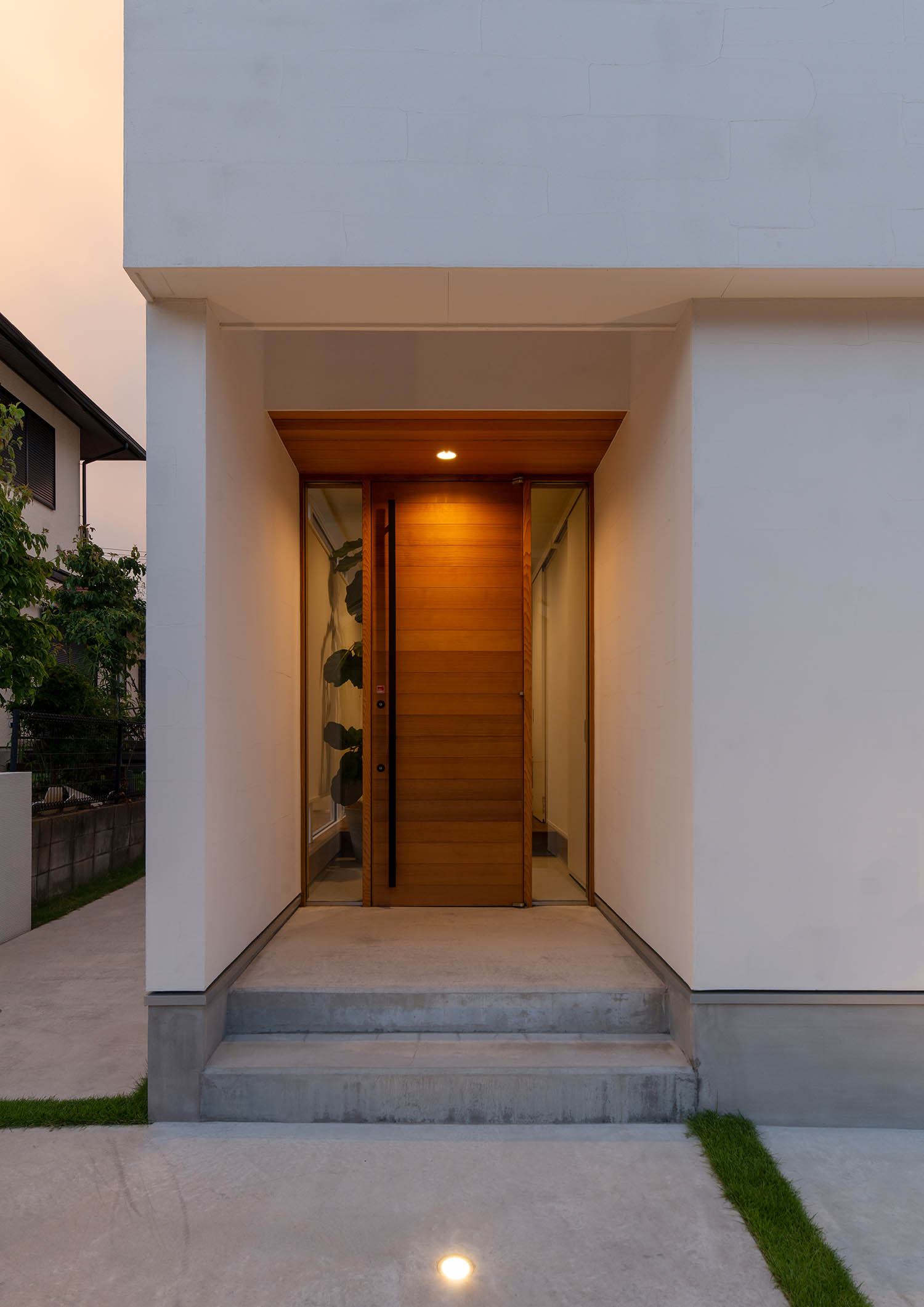 地面と軒天井に照明が埋め込まれた木の扉の玄関・デザイン住宅 注文住宅・デザイン住宅建築実例_『CASE663 シークエンス』_外観