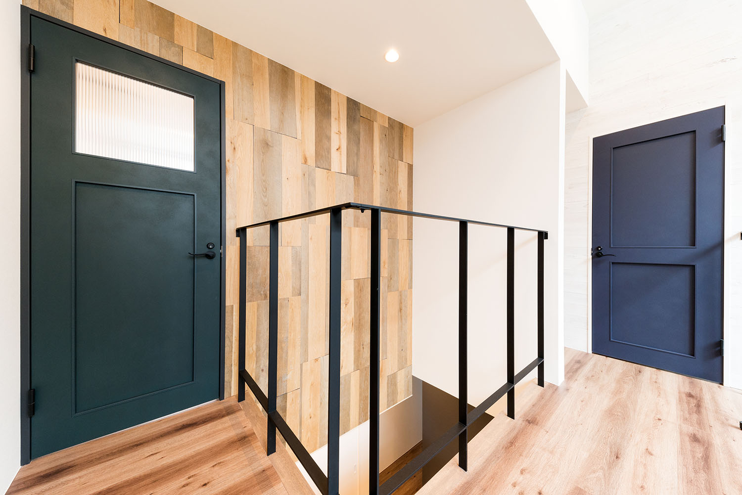 吹き抜けに面して手すりが設けられた廊下の先に、青や緑の扉が設けられている様子・デザイン住宅 注文住宅・デザイン住宅建築実例_『CASE664 『BOX in BOX』』_廊下