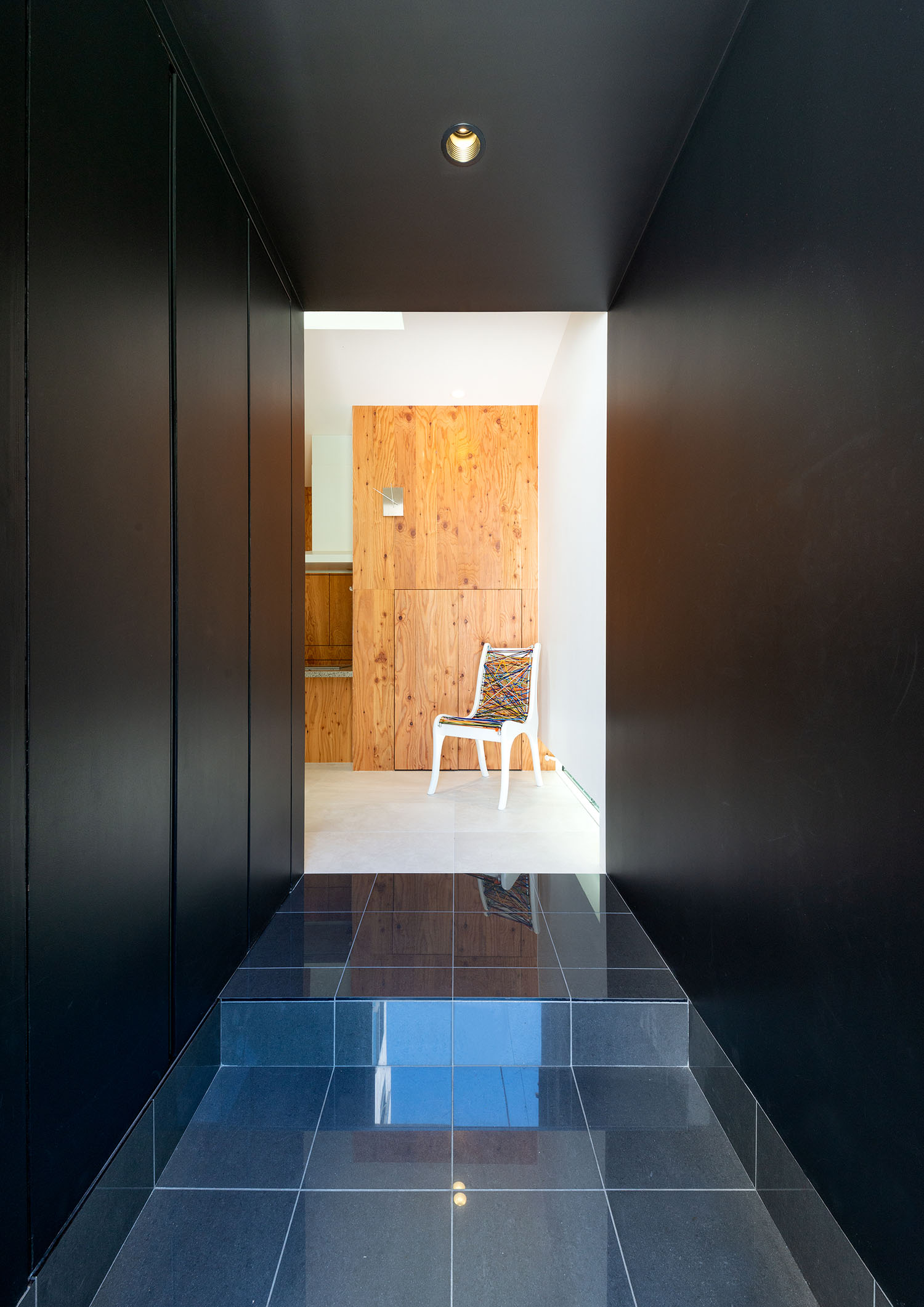 黒いタイルと壁の玄関の先に木の壁が広がる様子・デザイン住宅 注文住宅・デザイン住宅建築実例_『CASE665 LUCE』_玄関