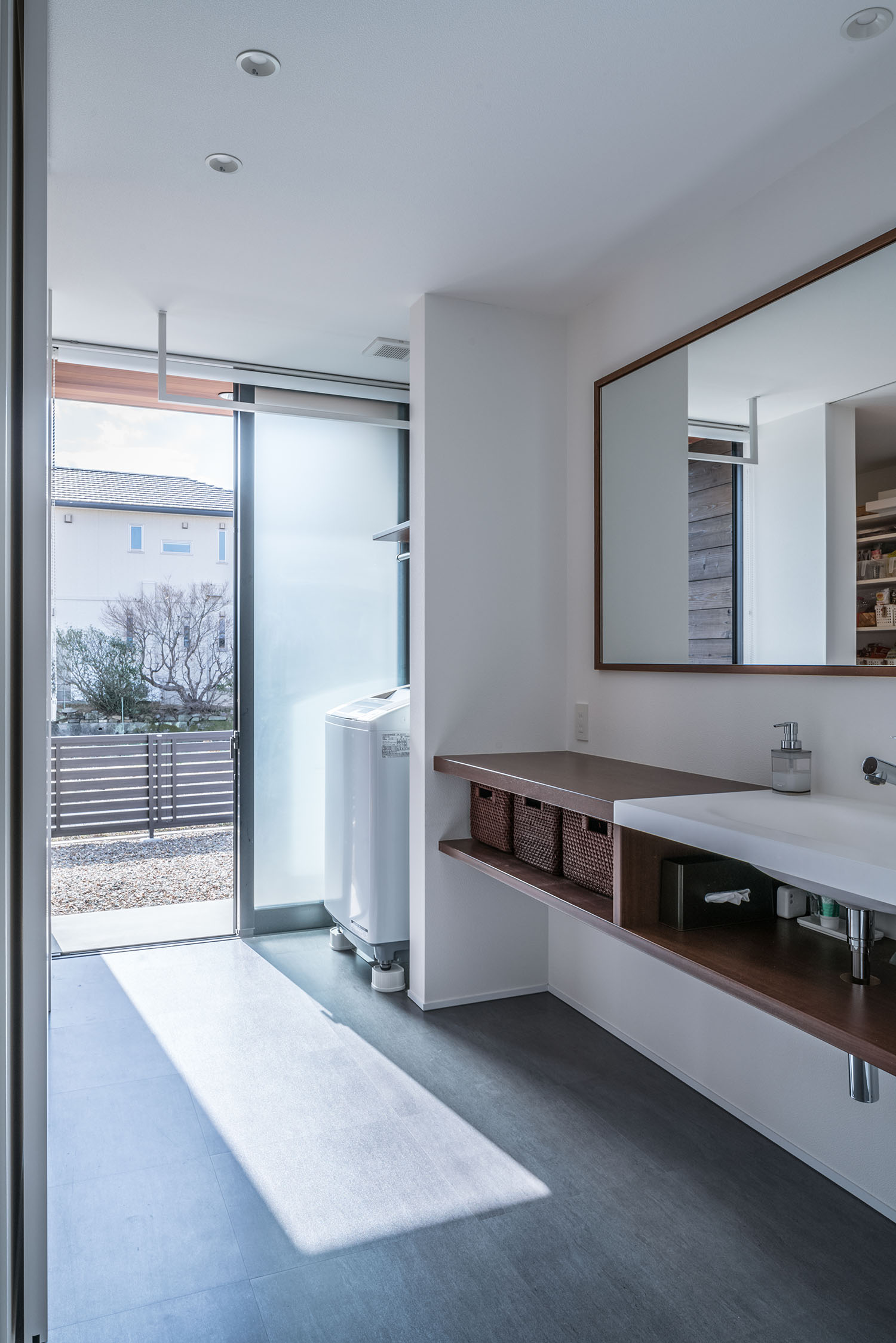 洗濯機のあるランドリールームの隣にテラスへ繋がる窓がある様子・デザイン住宅 注文住宅・デザイン住宅建築実例_『CASE671 実りの平屋』_浴室・洗面所