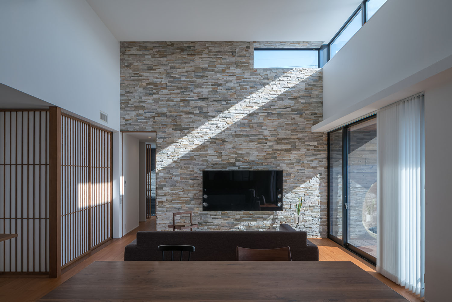 ハイサイドライトから自然光が入る、石の壁がアクセントになったLDK・デザイン住宅 注文住宅・デザイン住宅建築実例_『CASE671 実りの平屋』_LDK