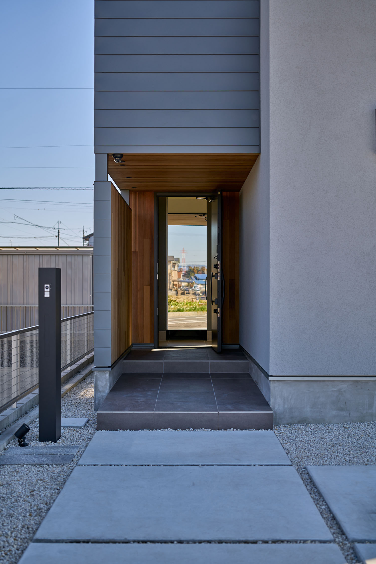玄関扉を開いた先に、外の景色が見える窓がある様子・デザイン住宅 注文住宅・デザイン住宅建築実例_『CASE670 静かな形の家』_外観
