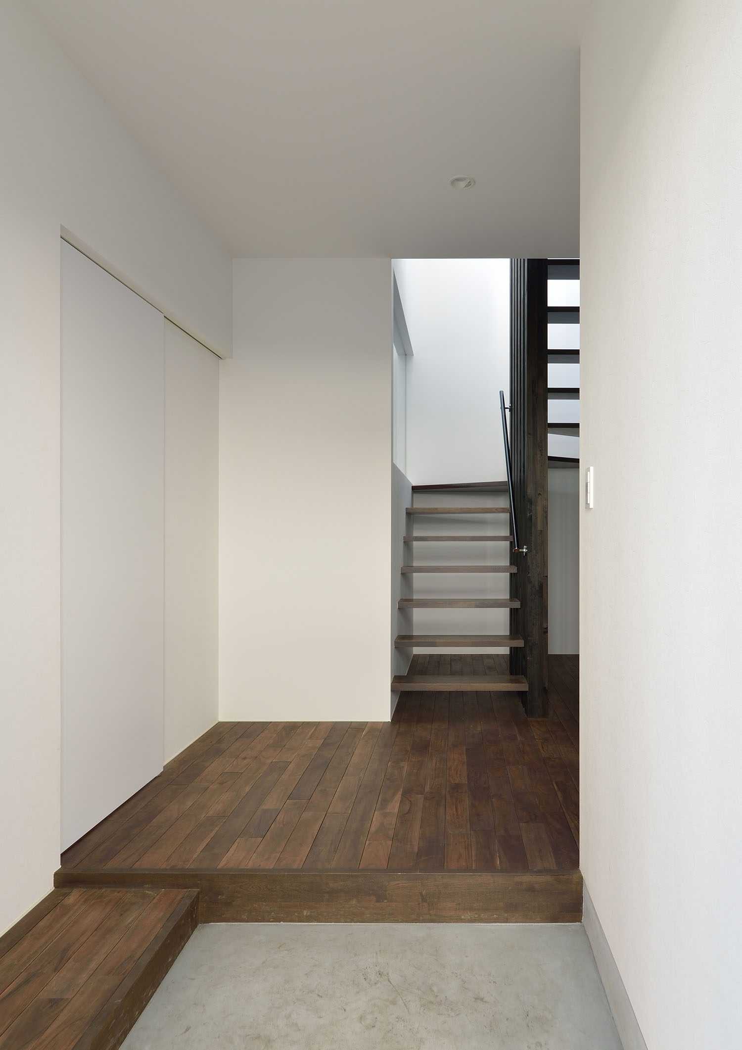 モルタルの玄関の先にフローリングとスケルトン階段が見える様子・デザイン住宅 注文住宅・デザイン住宅建築実例_『CASE672 Trick Art』_玄関