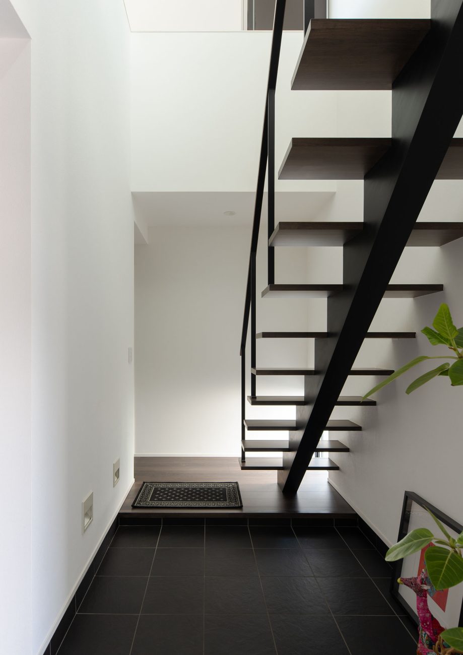 黒いタイルの玄関のそばにあるスケルトン階段・ラグジュアリーな住宅 注文住宅・デザイン住宅建築実例_『CASE673 Ganache』_玄関