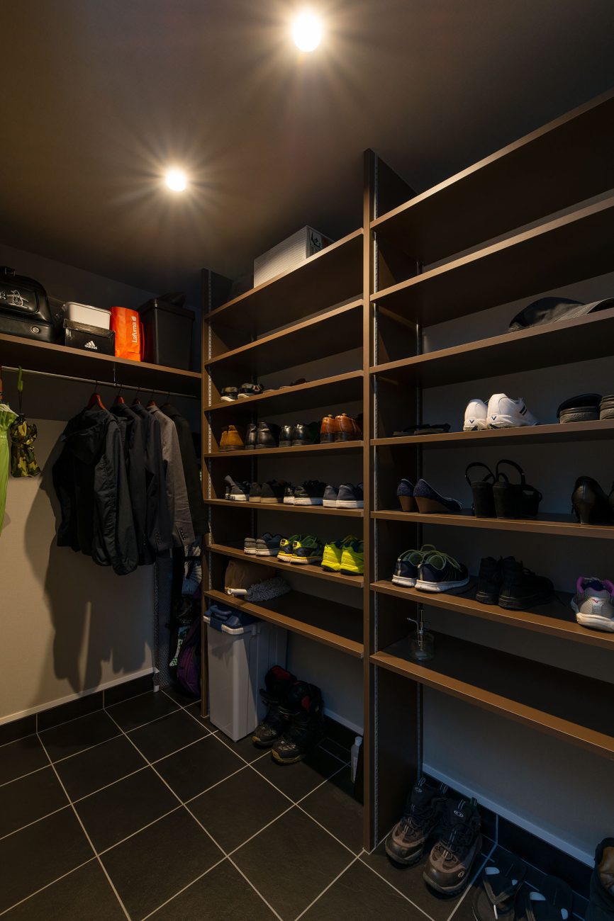 洋服を掛けることも出来る、黒いタイルの床のシューズインクローゼット・ラグジュアリーな住宅 注文住宅・デザイン住宅建築実例_『CASE673 Ganache』_玄関