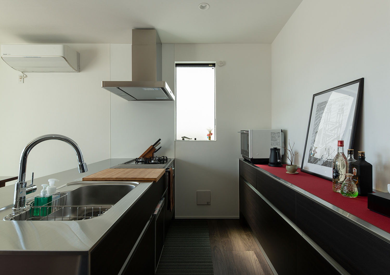 ステンレスのペニンシュラキッチンの反対側に黒いカップボードが取り付けられている様子・ラグジュアリーな住宅 注文住宅・デザイン住宅建築実例_『CASE673 Ganache』_キッチン