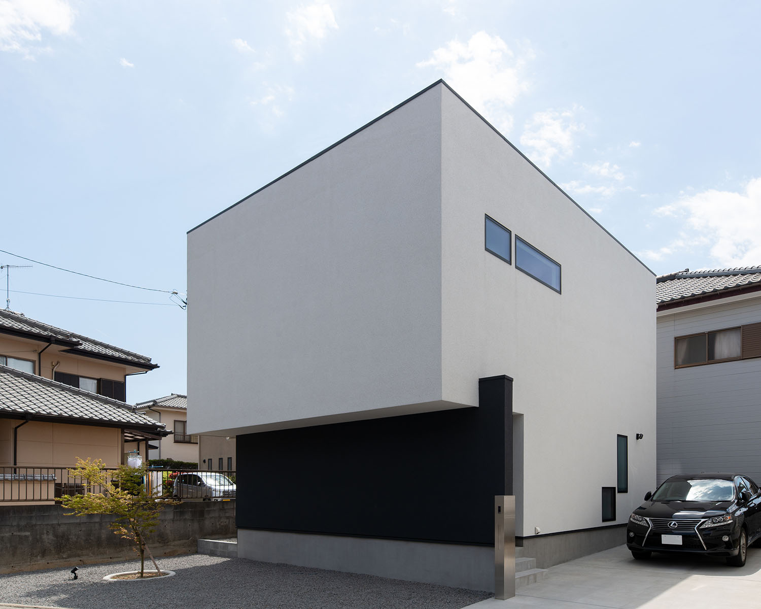 白いキューブ状の外観にスリット窓があり、黒い車が一台止められている住宅・デザイン住宅 注文住宅・デザイン住宅建築実例_『CASE673 Ganache』_外観
