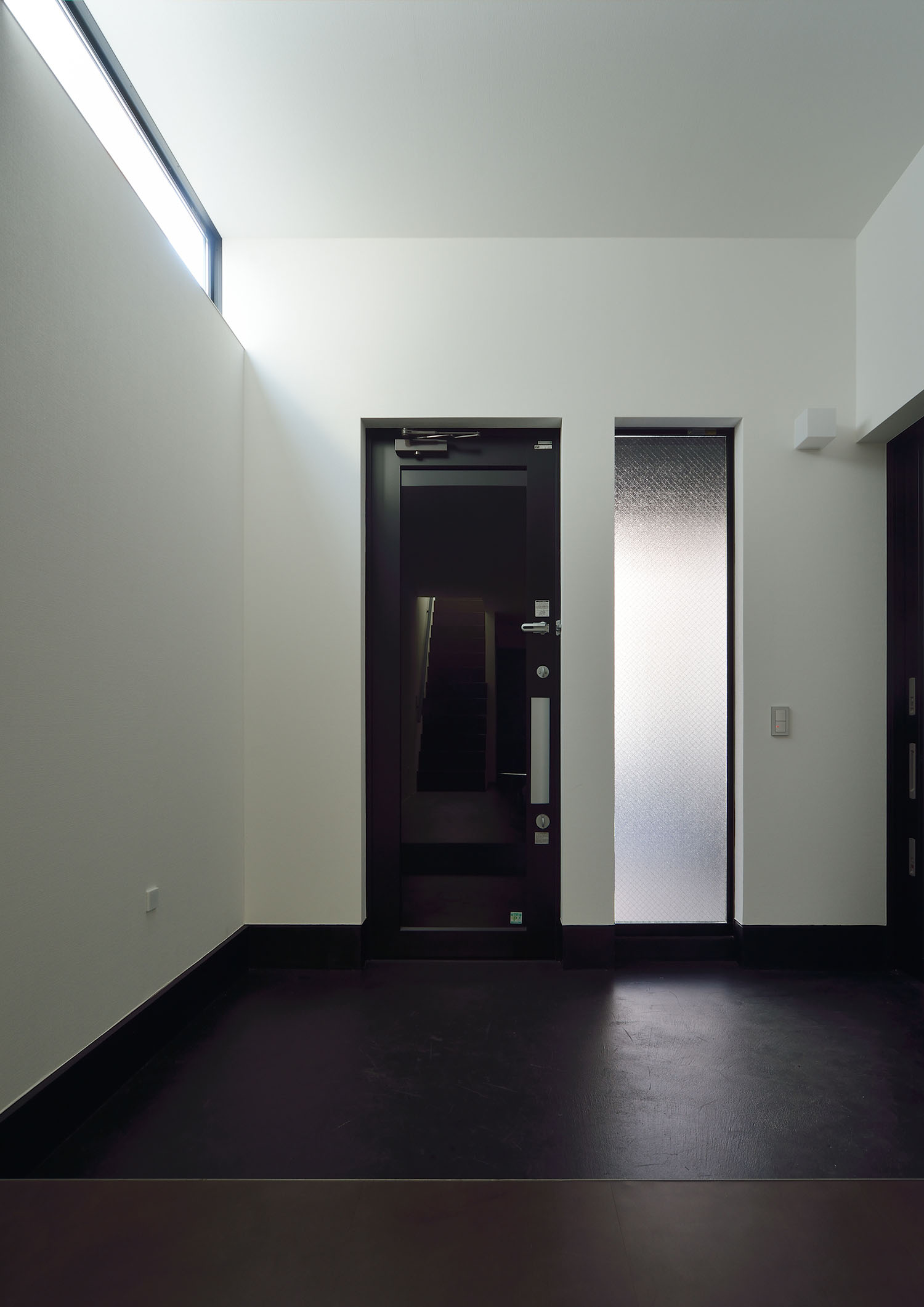 黒い玄関扉の隣にスリット窓がある様子・デザイン住宅 注文住宅・デザイン住宅建築実例_『CASE676 箱を包む小屋裏』_玄関