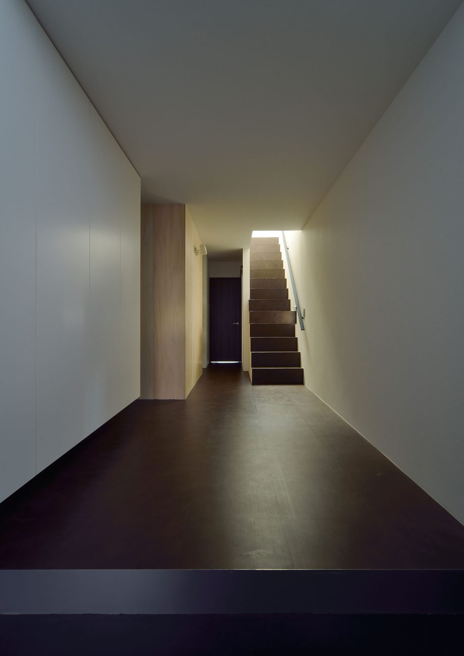 黒い玄関の先に、黒い床の廊下や階段が広がっている様子・デザイン住宅 注文住宅・デザイン住宅建築実例_『CASE676 箱を包む小屋裏』_玄関
