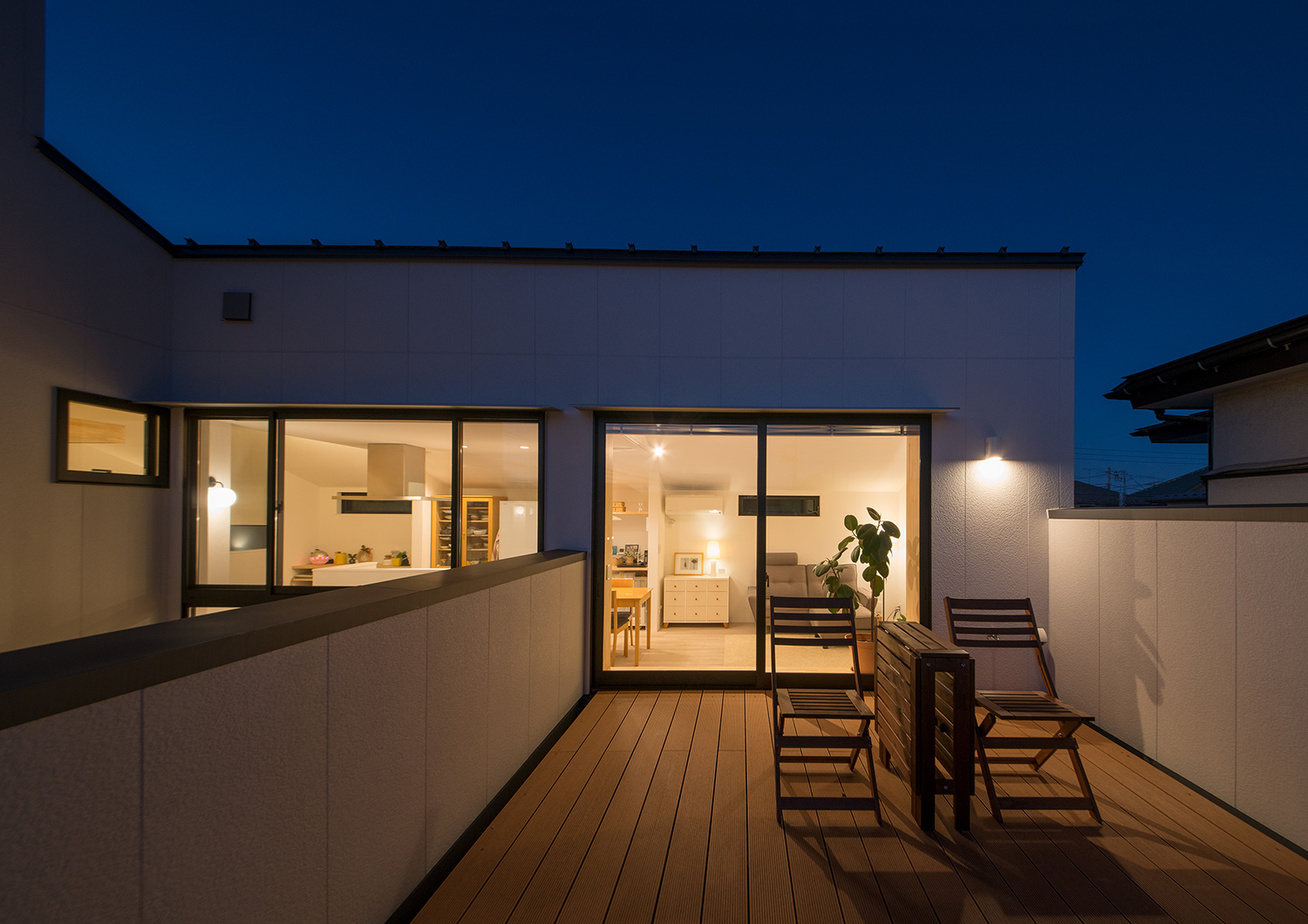 木の椅子が置かれたウッドデッキのバルコニーが照明で照らされる様子・デザイン住宅 注文住宅・デザイン住宅建築実例_『CASE677 中庭が繋ぐ家族の気配』_テラス・バルコニー