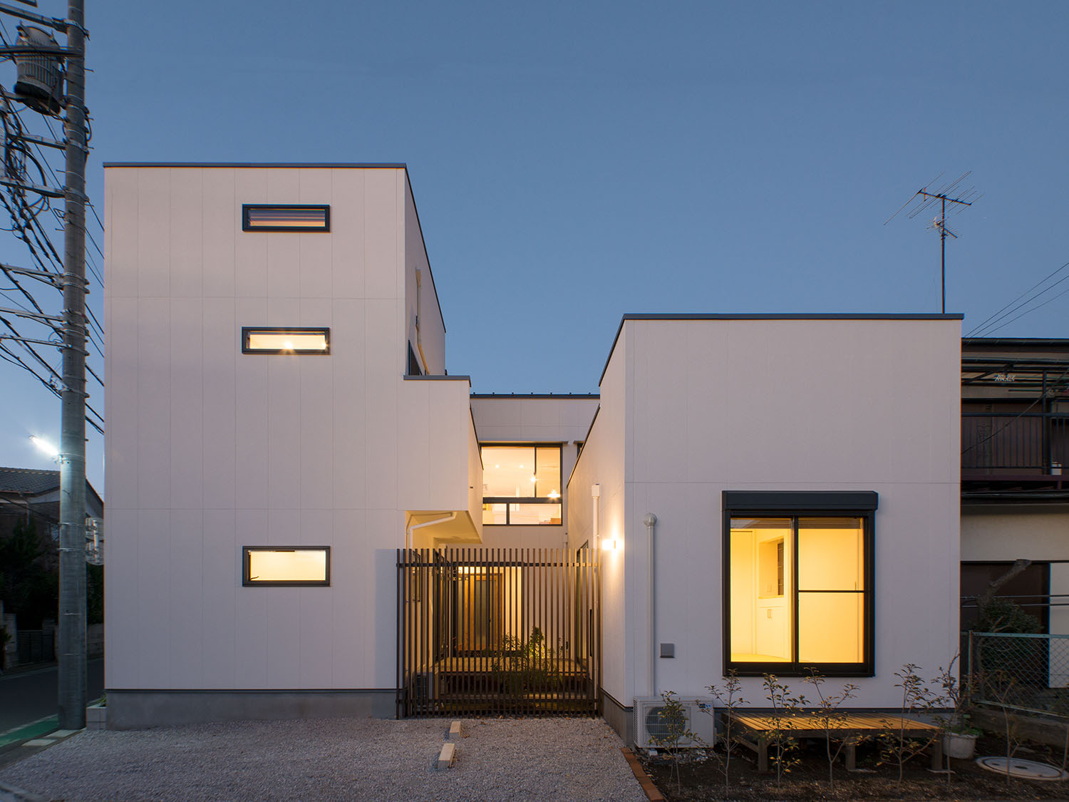 スリット窓やテラスに面する窓から光が漏れる白い外壁の住宅・デザイン住宅 注文住宅・デザイン住宅建築実例_『CASE677 中庭が繋ぐ家族の気配』_外観