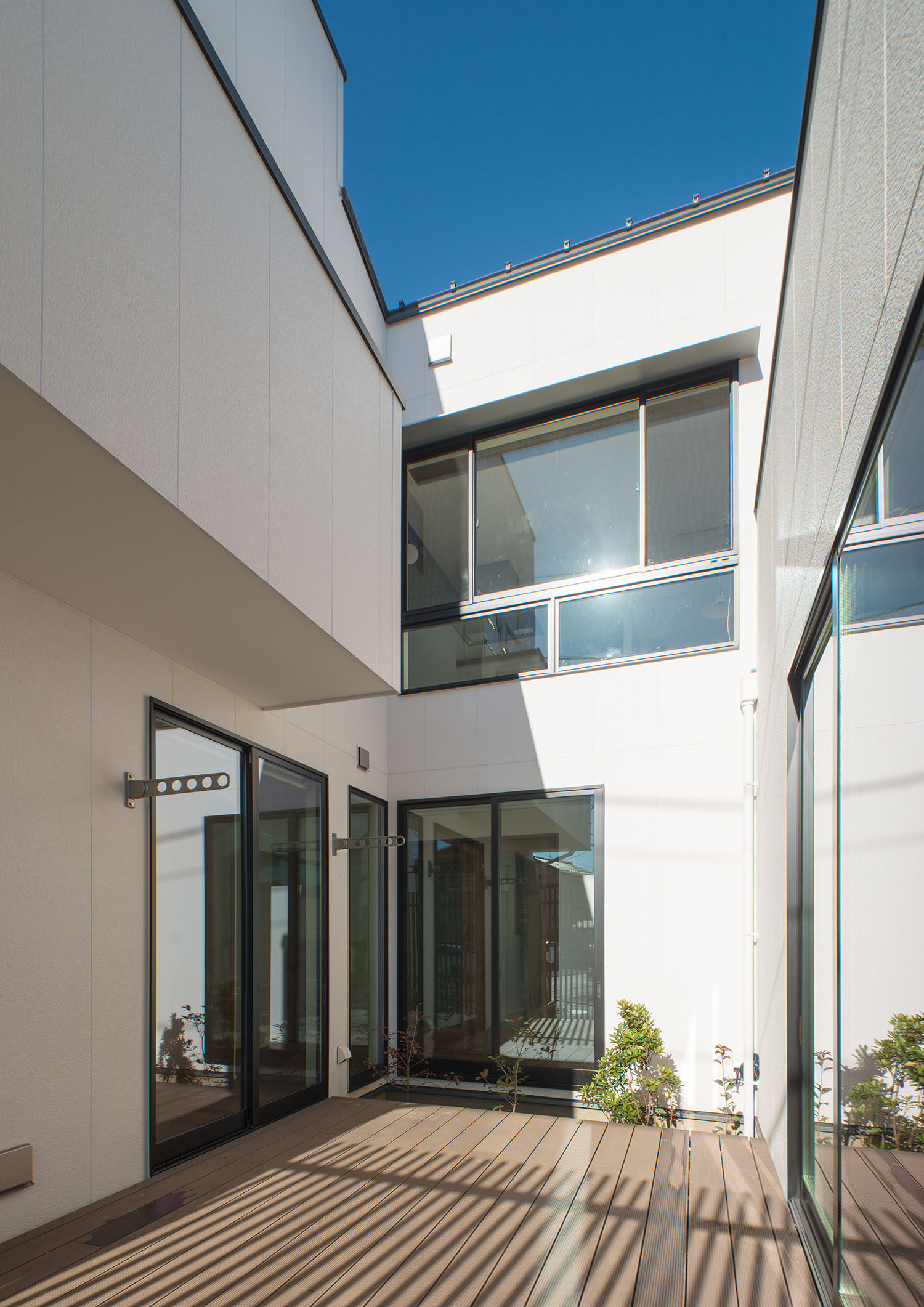 ウッドデッキの中庭に窓が多く面している、白い外壁の住宅・デザイン住宅 注文住宅・デザイン住宅建築実例_『CASE677 中庭が繋ぐ家族の気配』_中庭