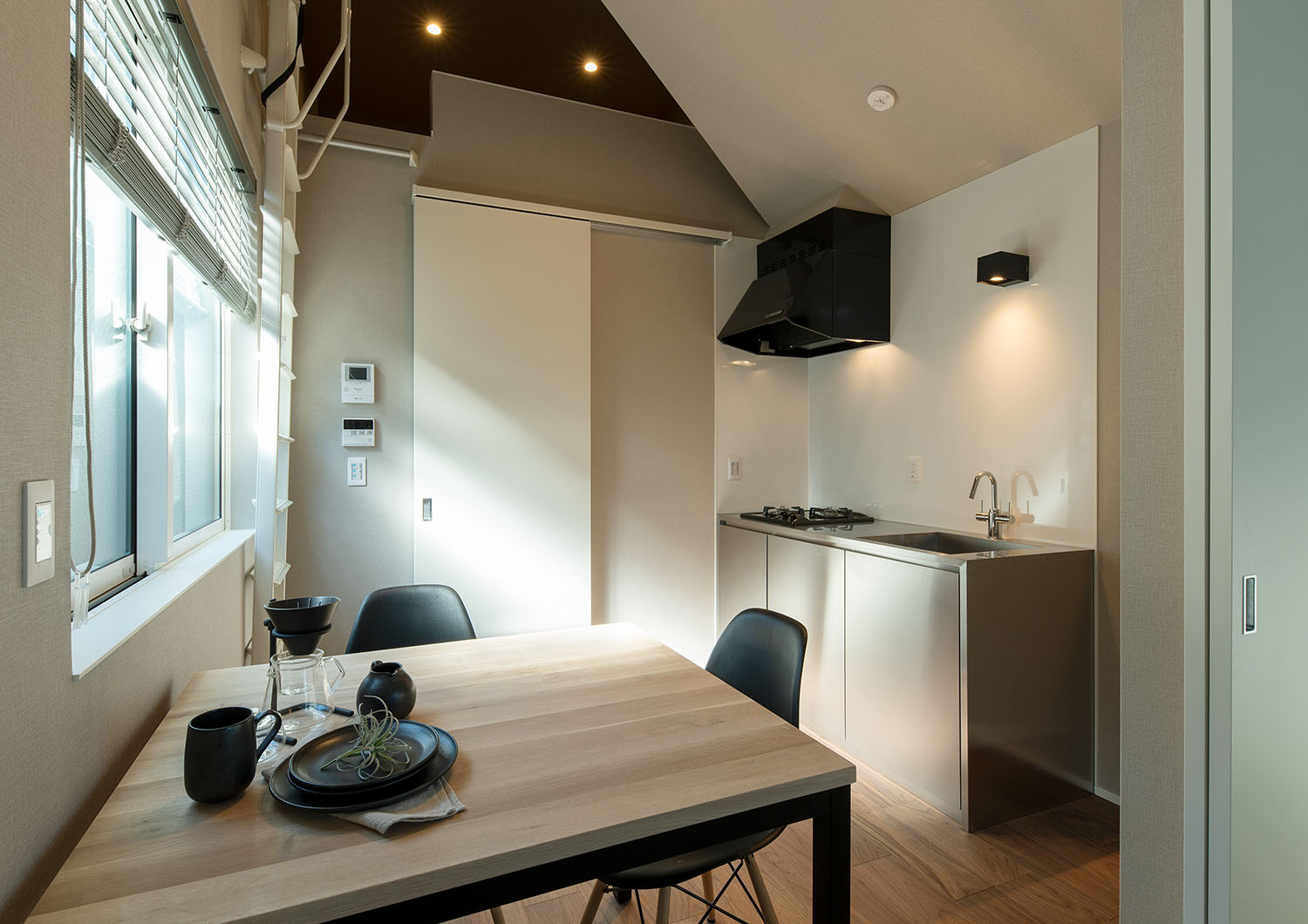 ステンレスの壁付けキッチンがあり、レンジフードやインテリアが黒で統一された部屋・賃貸併用住宅 注文住宅・デザイン住宅建築実例_『CASE681  penche'　「パンシェ」の家』_LDK