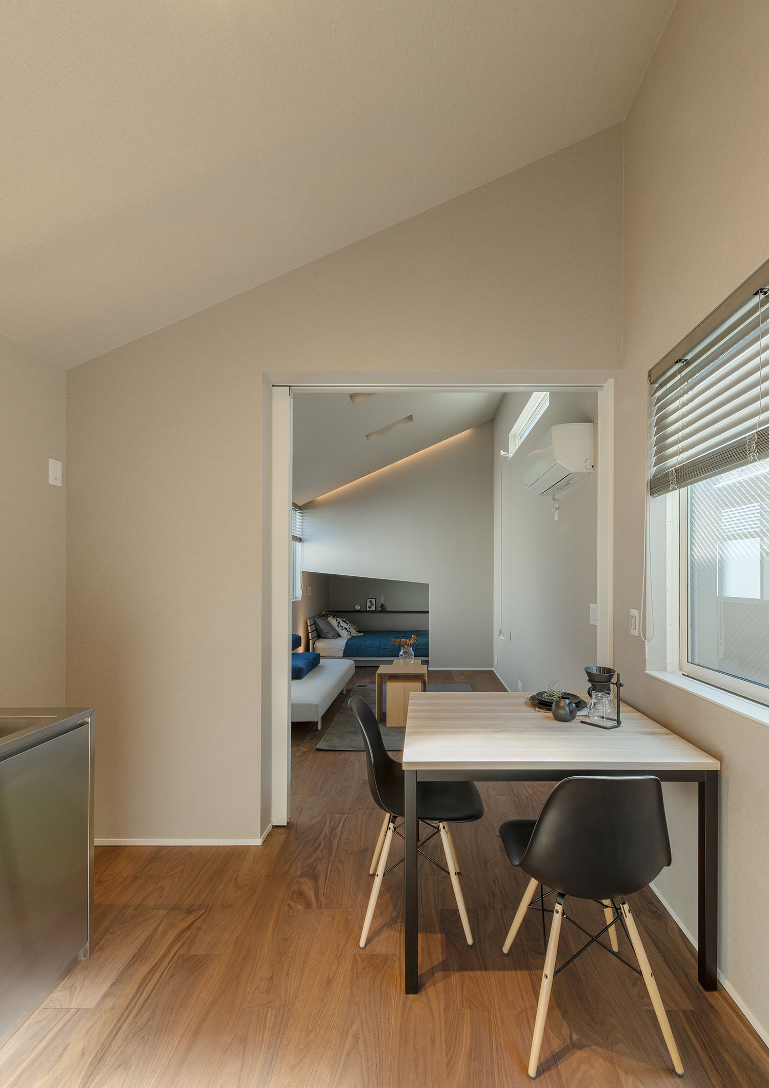 テーブルと黒い椅子があるダイニングからリビングを見た様子・賃貸併用住宅 注文住宅・デザイン住宅建築実例_『CASE681  penche'　「パンシェ」の家』_LDK