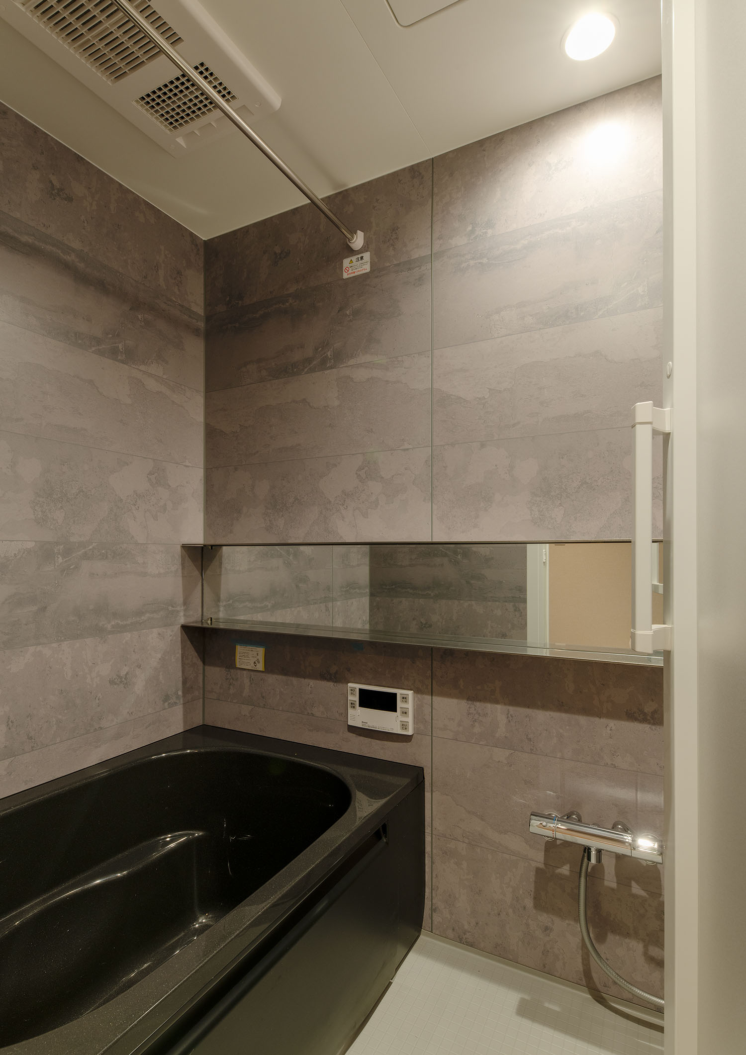 石のような壁で、黒いバスタブがある浴室・賃貸併用住宅 注文住宅・デザイン住宅建築実例_『CASE681  penche'　「パンシェ」の家』_浴室・洗面所