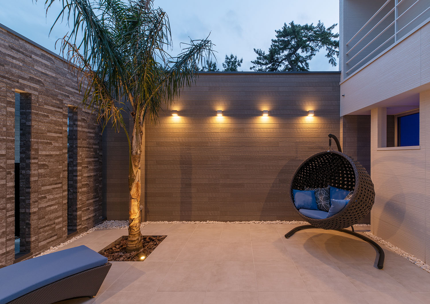 壁に間接照明が取り付けられた、ヤシの木やハンモックチェアがある中庭・デザイン住宅 注文住宅・デザイン住宅建築実例_『CASE682  Casa de Resort』_中庭