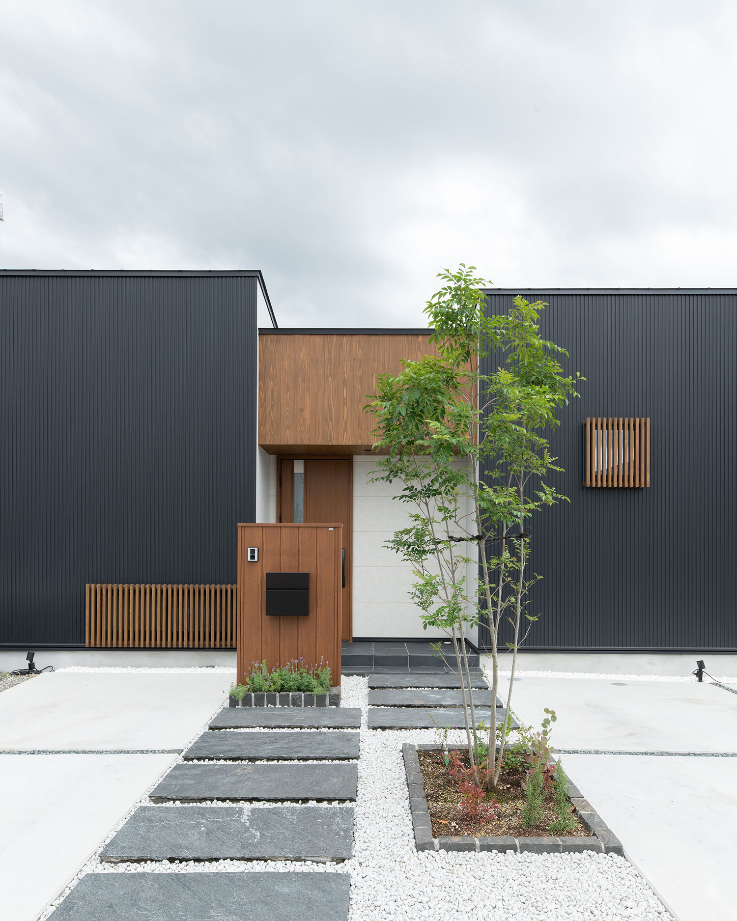 正面にシンボルツリーがある、黒い外壁に木材がアクセントとなった住宅の外観・デザイン住宅 注文住宅・デザイン住宅建築実例_『CASE683  丘の上のハウス』_外観