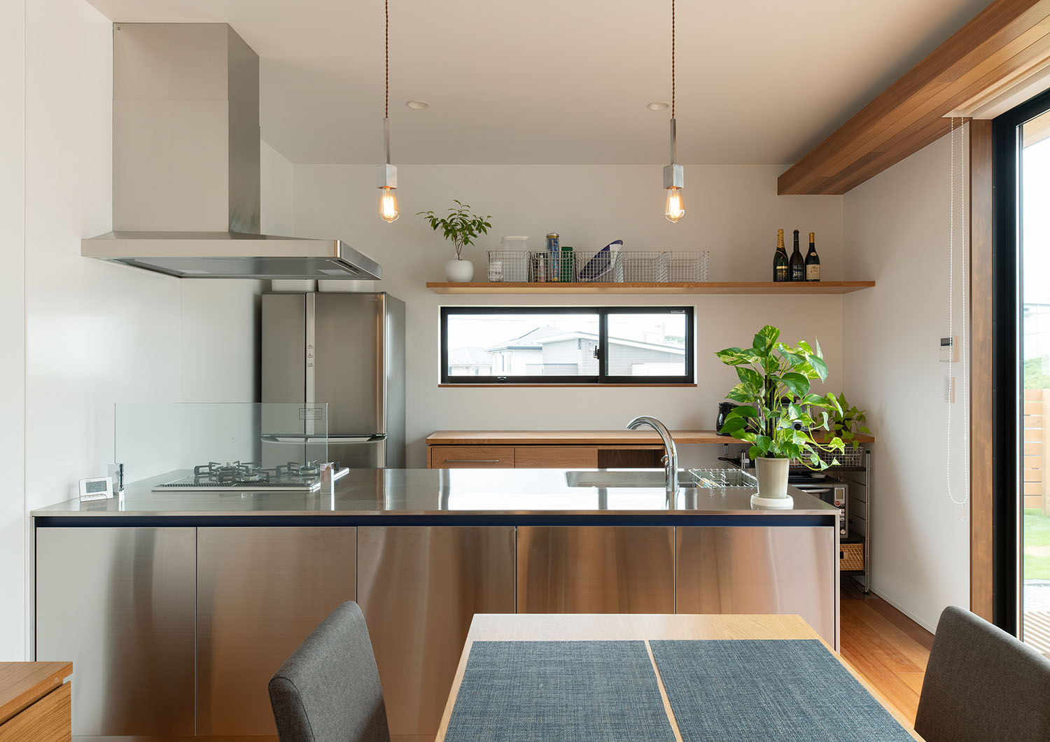 天井からペンダントライトが吊り下げられているステンレスのペニンシュラキッチン・デザイン住宅 注文住宅・デザイン住宅建築実例_『CASE683  丘の上のハウス』_キッチン
