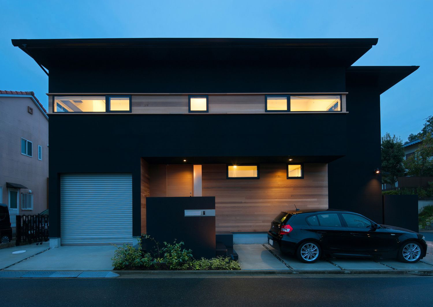 シャッター付きガレージと駐車場が両方あるおしゃれな外観の家・デザイン住宅