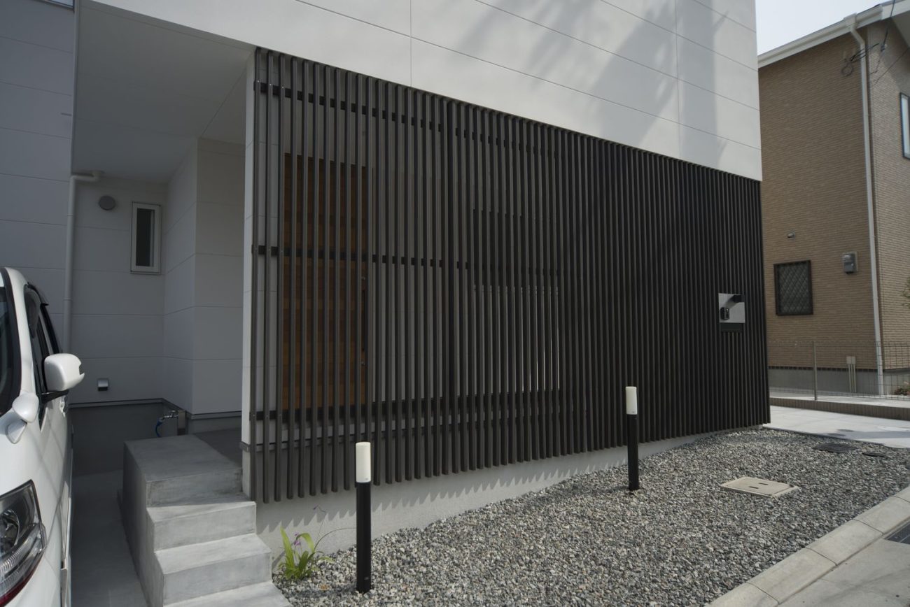 黒いルーバーの目隠しを取り付けた玄関アプローチ・デザイン住宅