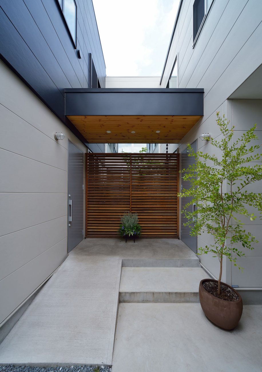 木目の軒天井や木のルーバーがあるコンクリートの玄関ポーチ・デザイン住宅