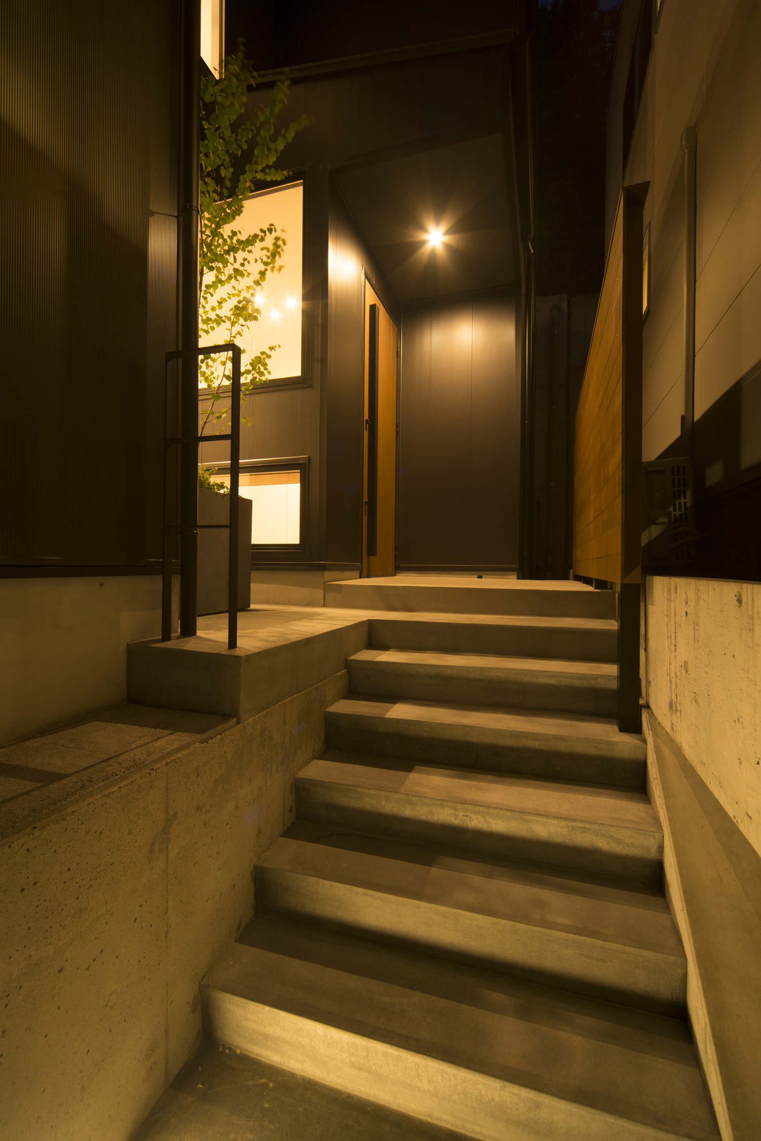 コンクリ―トの階段アプローチの先にあるプライベートな玄関・デザイン住宅